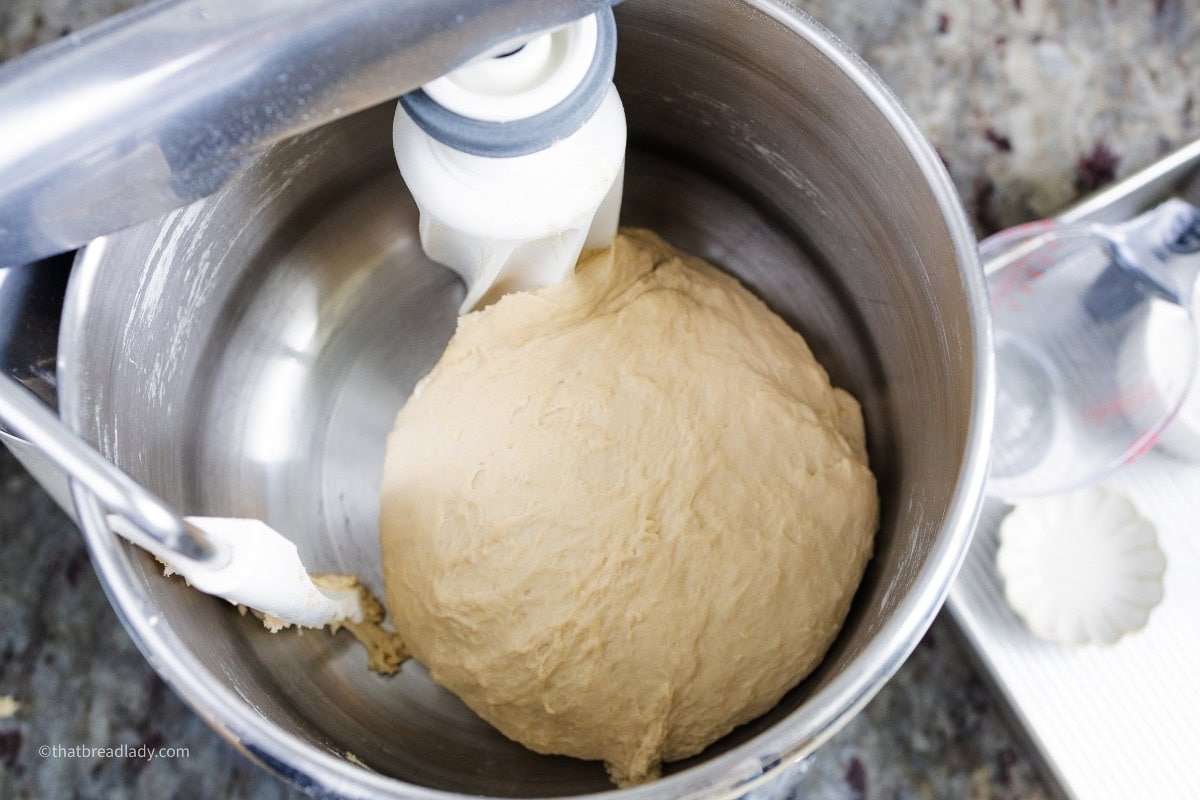 Soft pretzel dough inside the steel bowl of a stand mixer.
