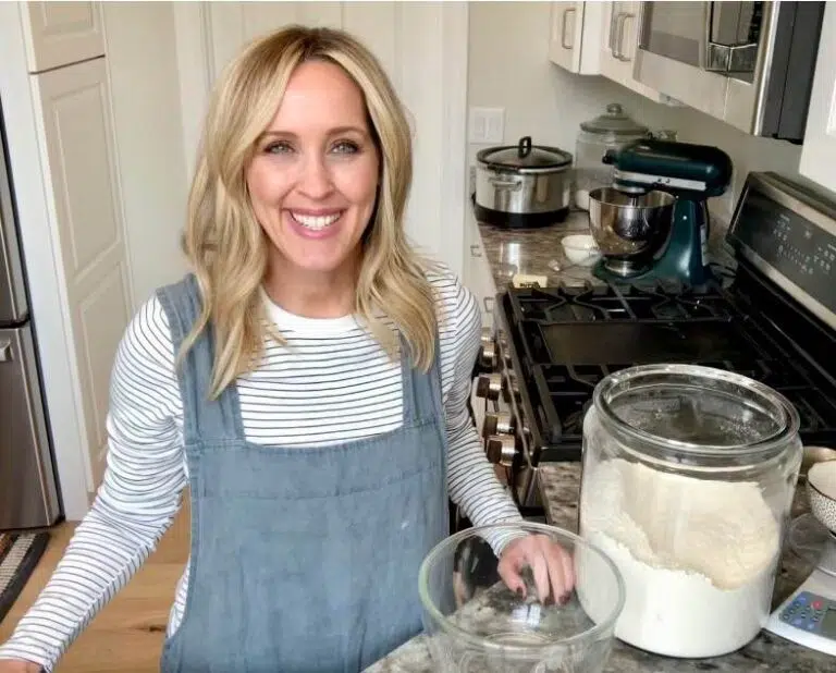 Heather Thomas, creator of That Bread Lady, standing in her kitchen, at the counter, with a jar of bread flour.
