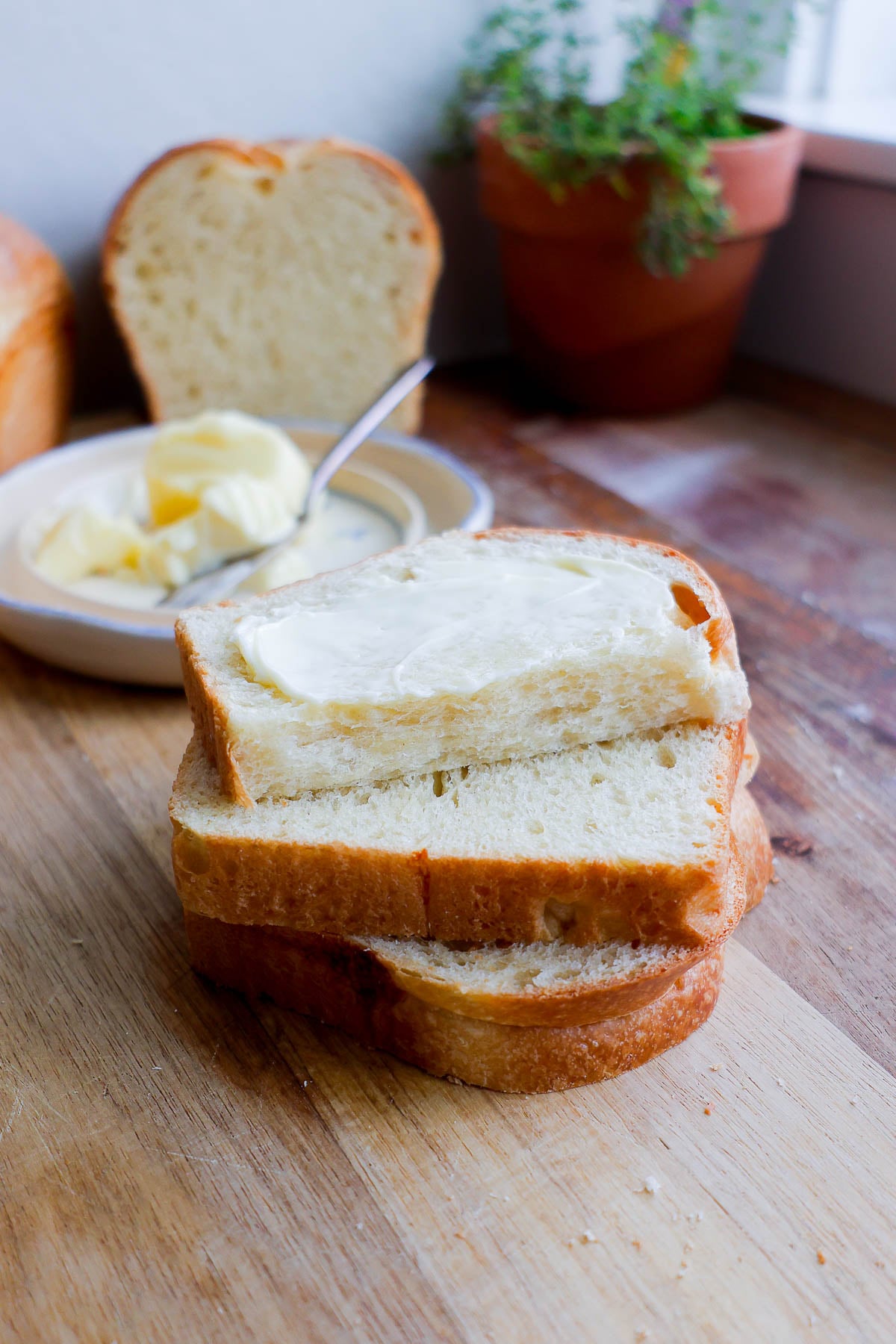 Three slices of french brioche bread stack on top of each other with the top slice buttered.