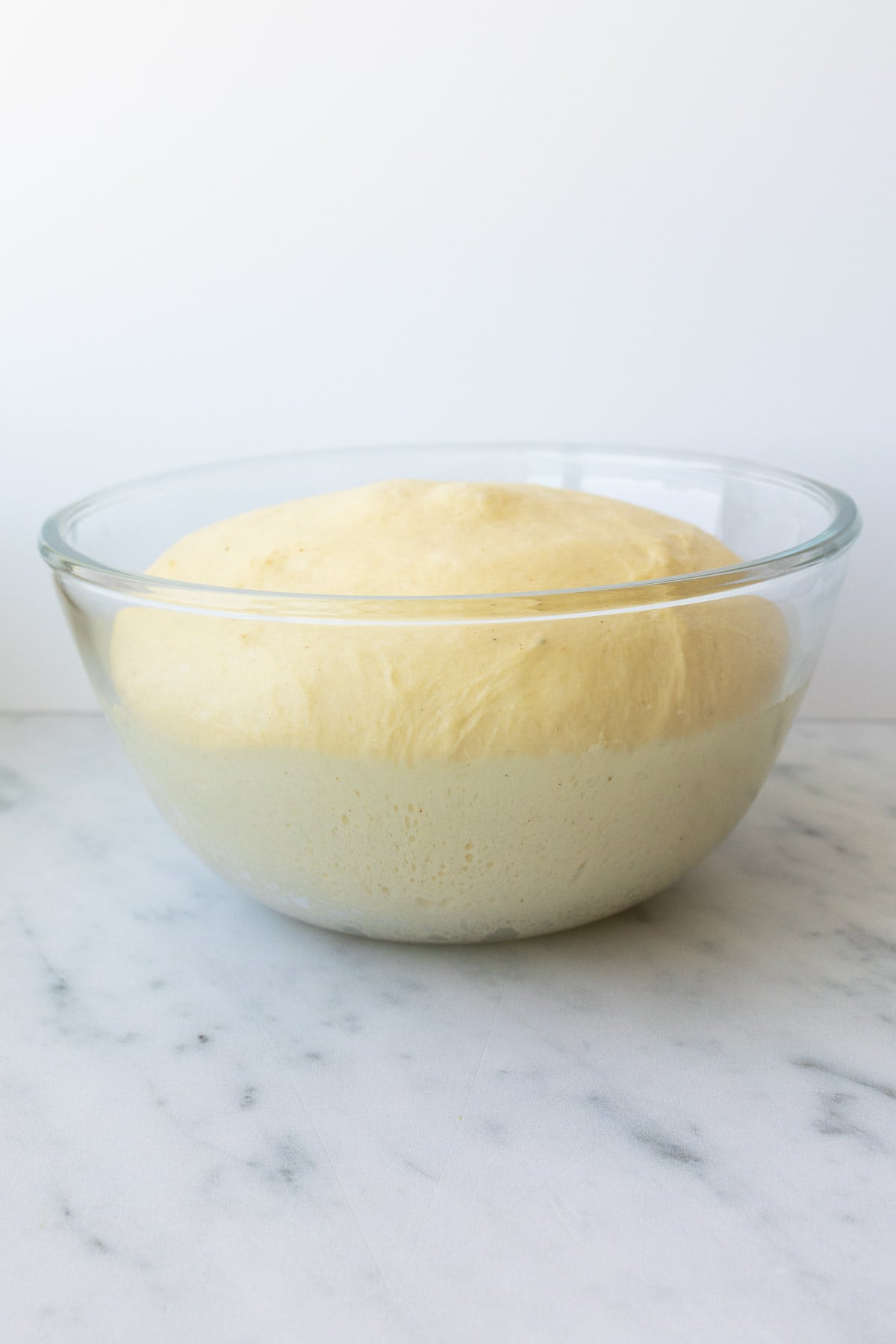 Risen French brioche bread in a glass bowl.