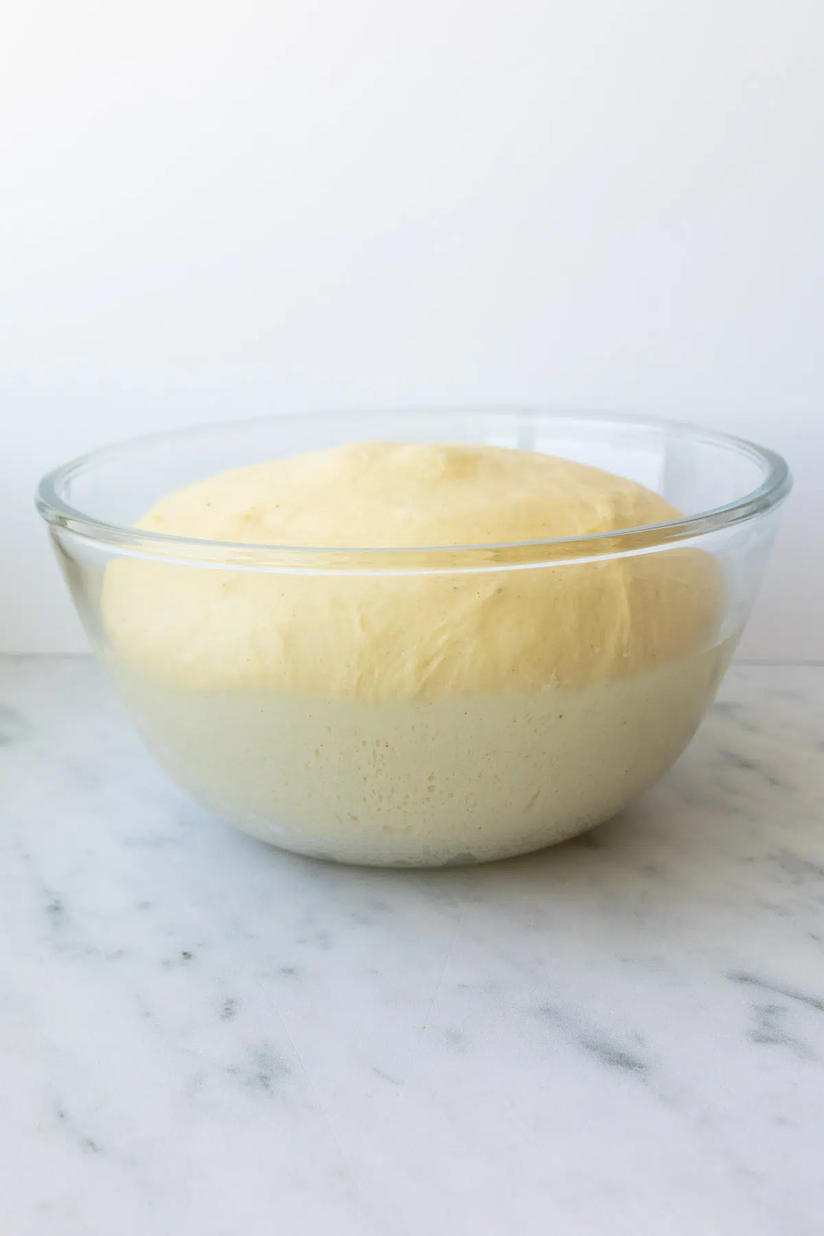 Risen French brioche bread in a glass bowl.