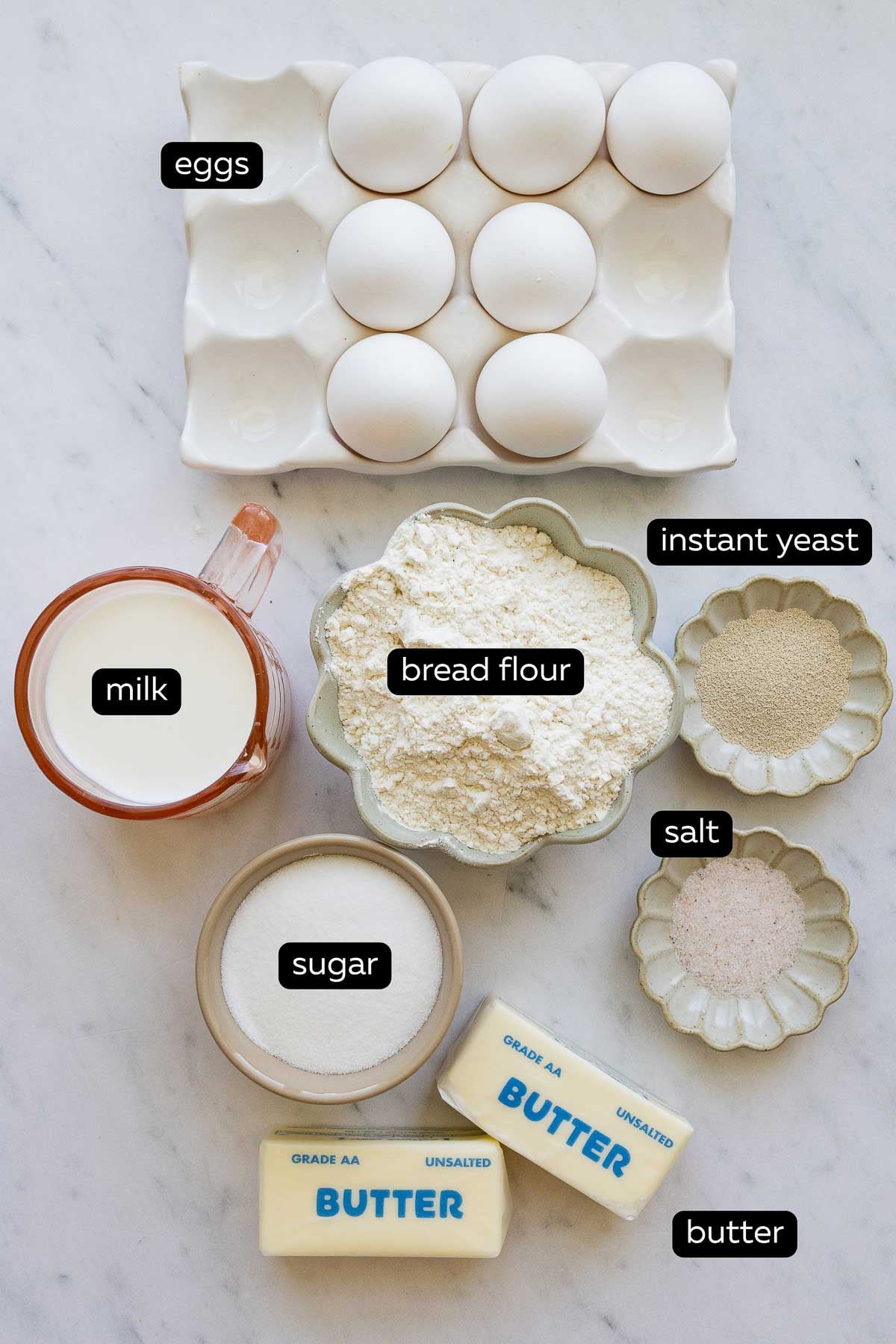 All the ingredients for French brioche bread including eggs, milk, instant yeast, bread flour, sugar, salt and butter.