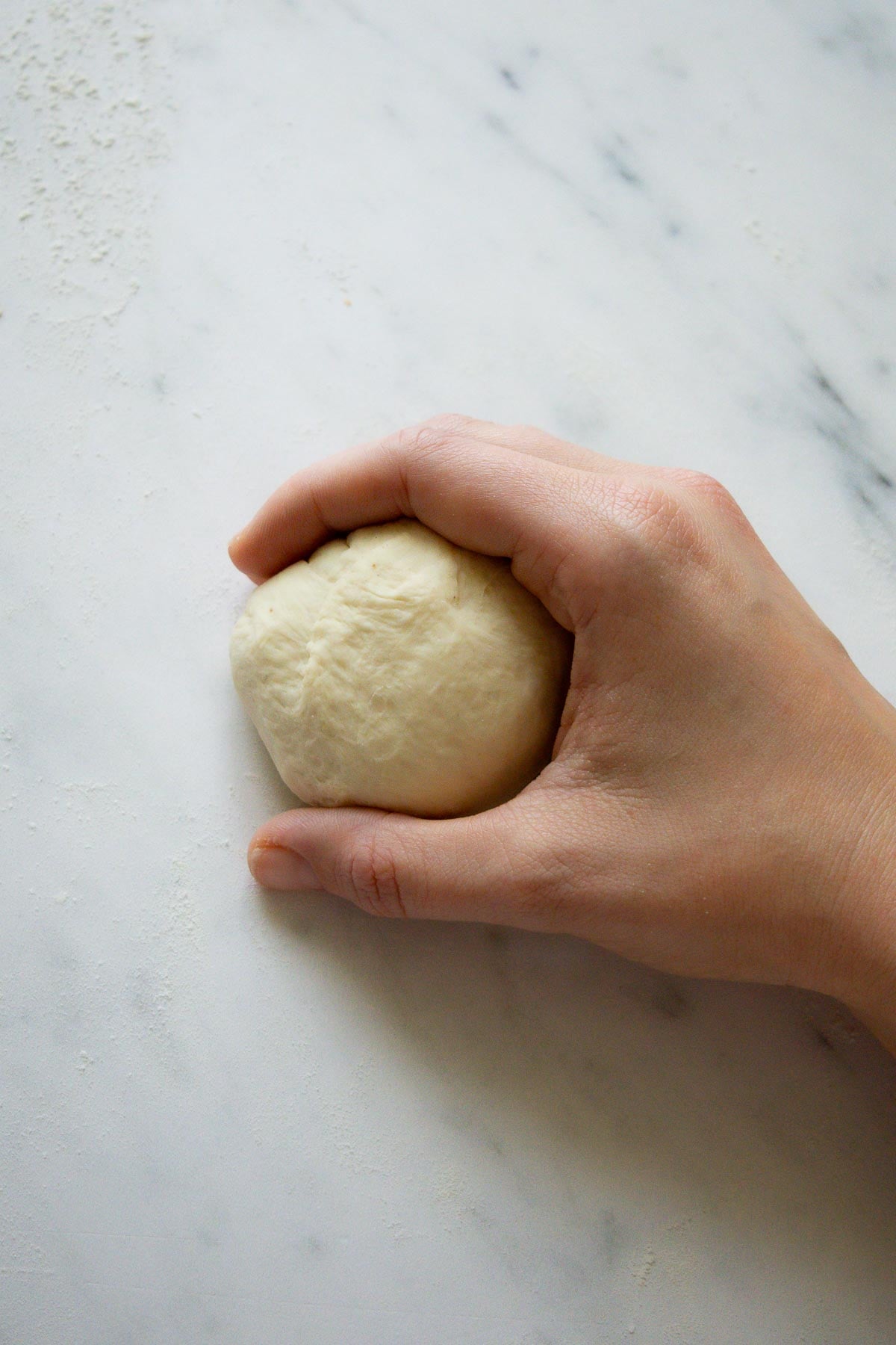 A hand cupping a round ball. of French brioche dough.