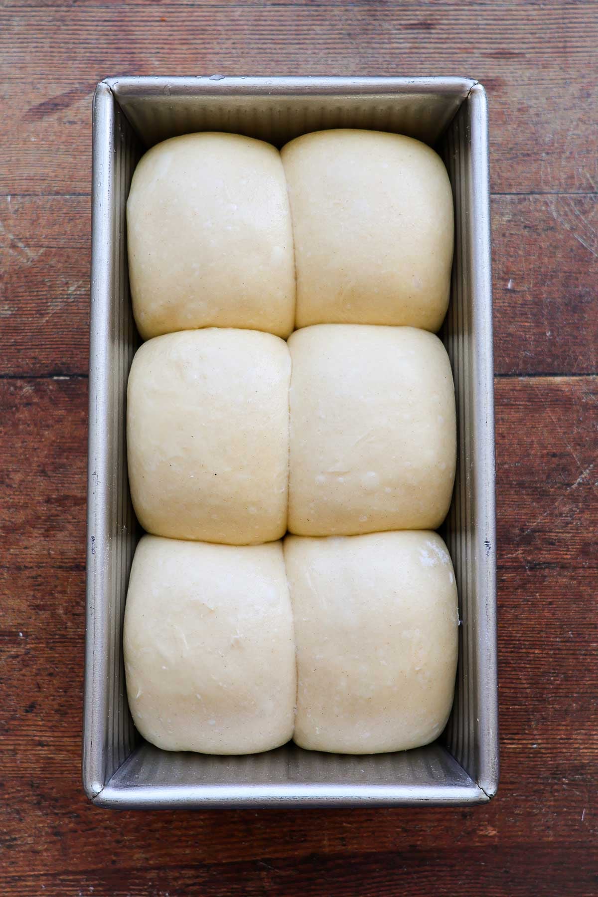 A loaf of risen french brioche bread in a metal loaf pan.