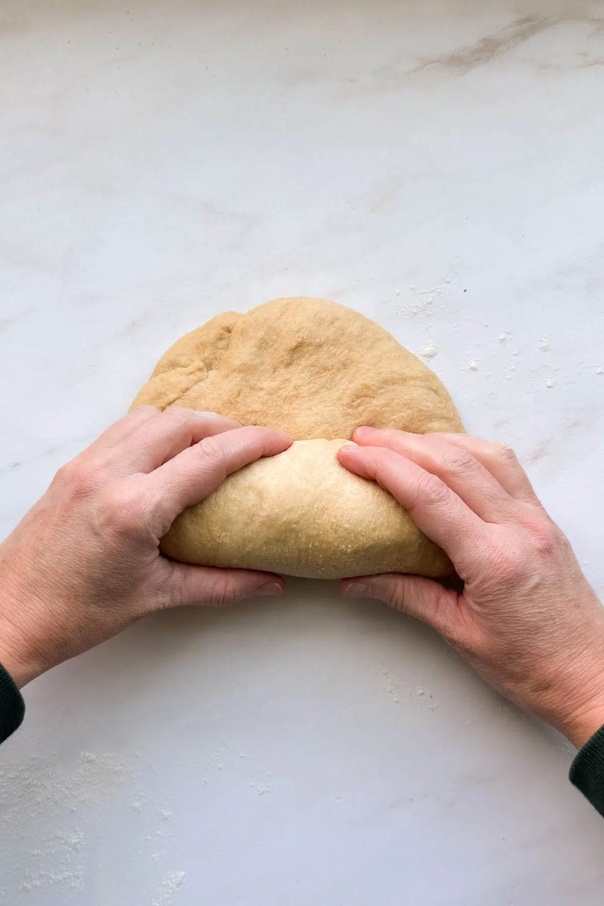 Two hands rolling up the loaf of honey whole wheat bread.
