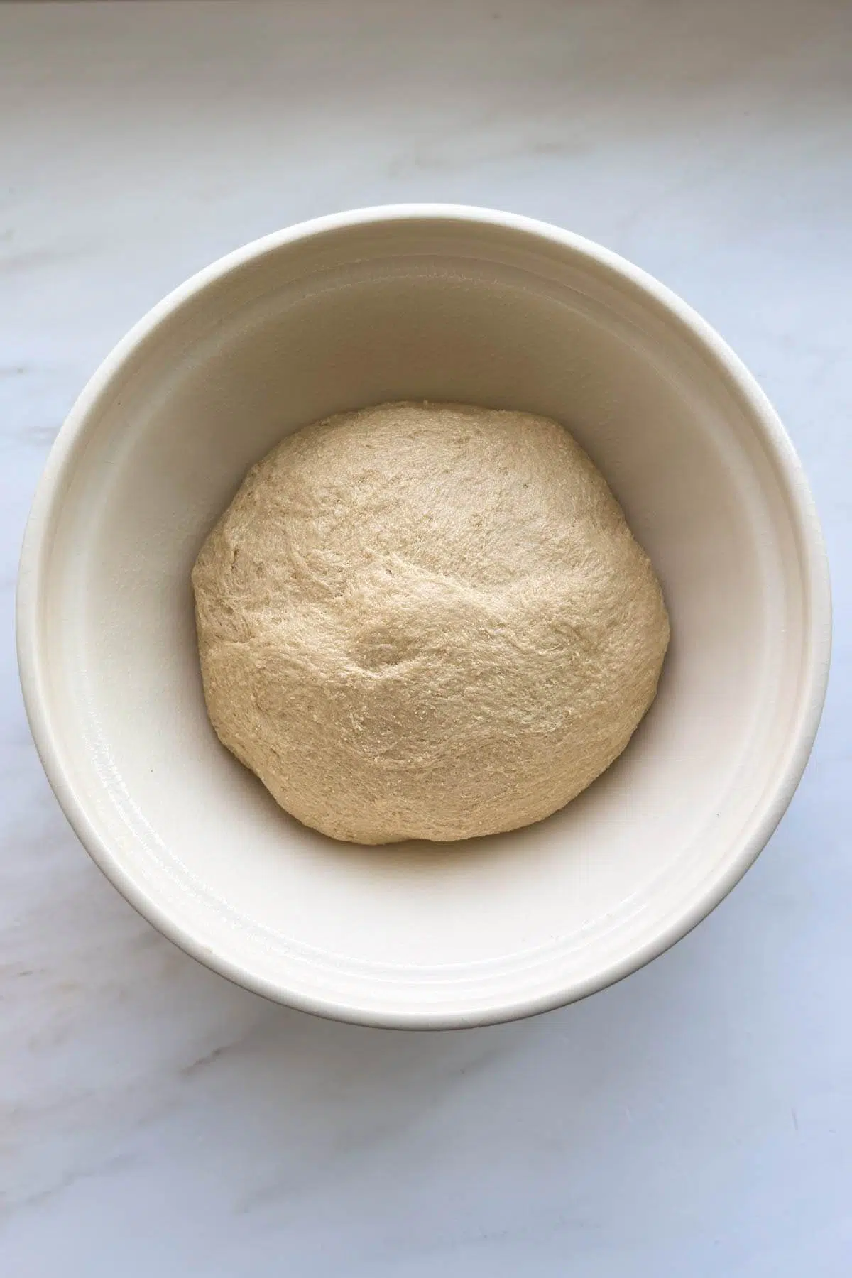 The honey whole wheat bread dough resting in a bowl.