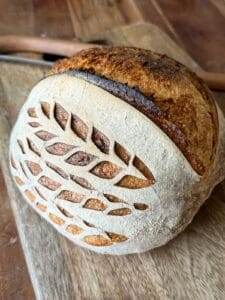 A loaf of sourdough bread on a wood bread board.