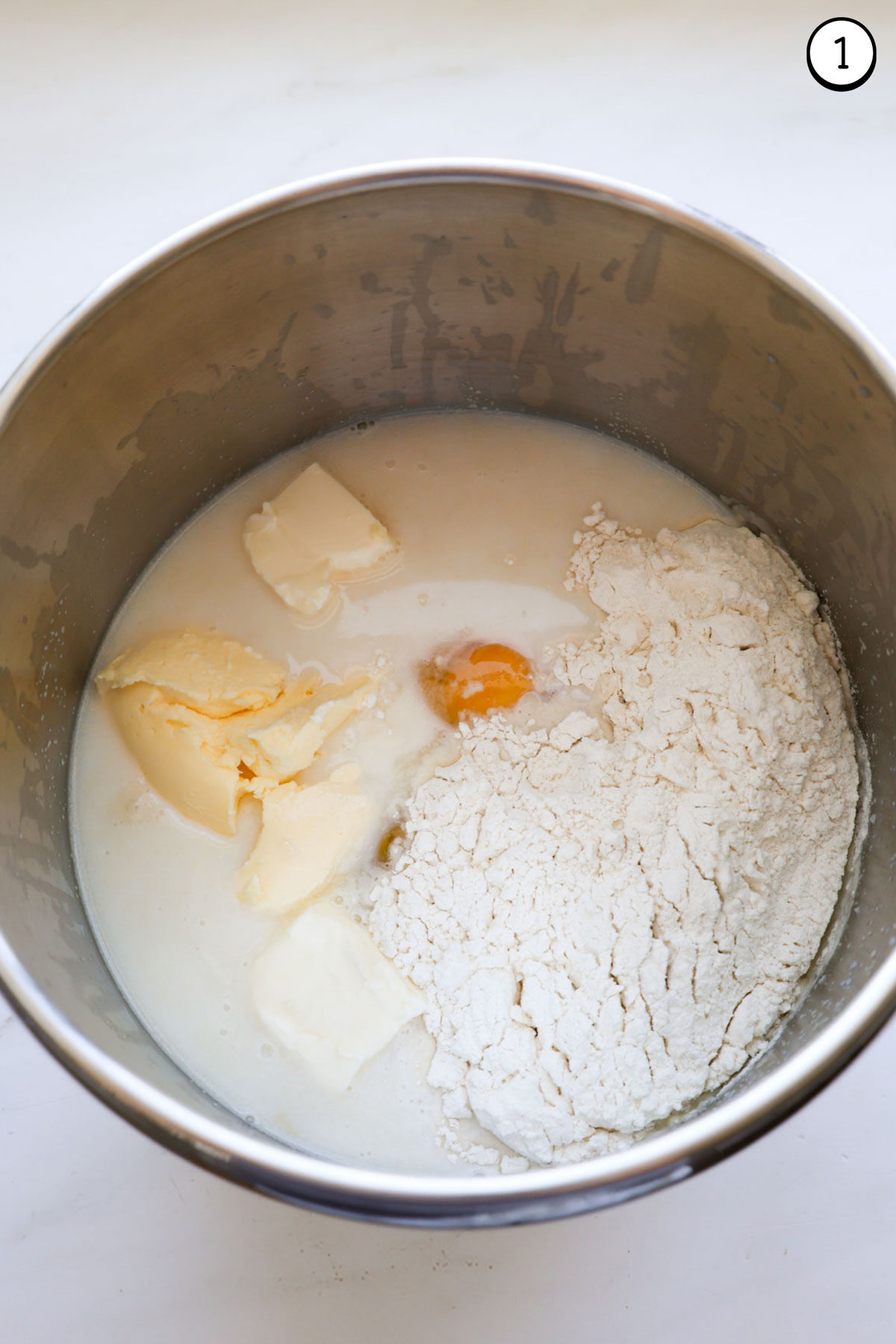 A stainless steel mixing bowl with all the ingredients for crescent rolls, unmixed.