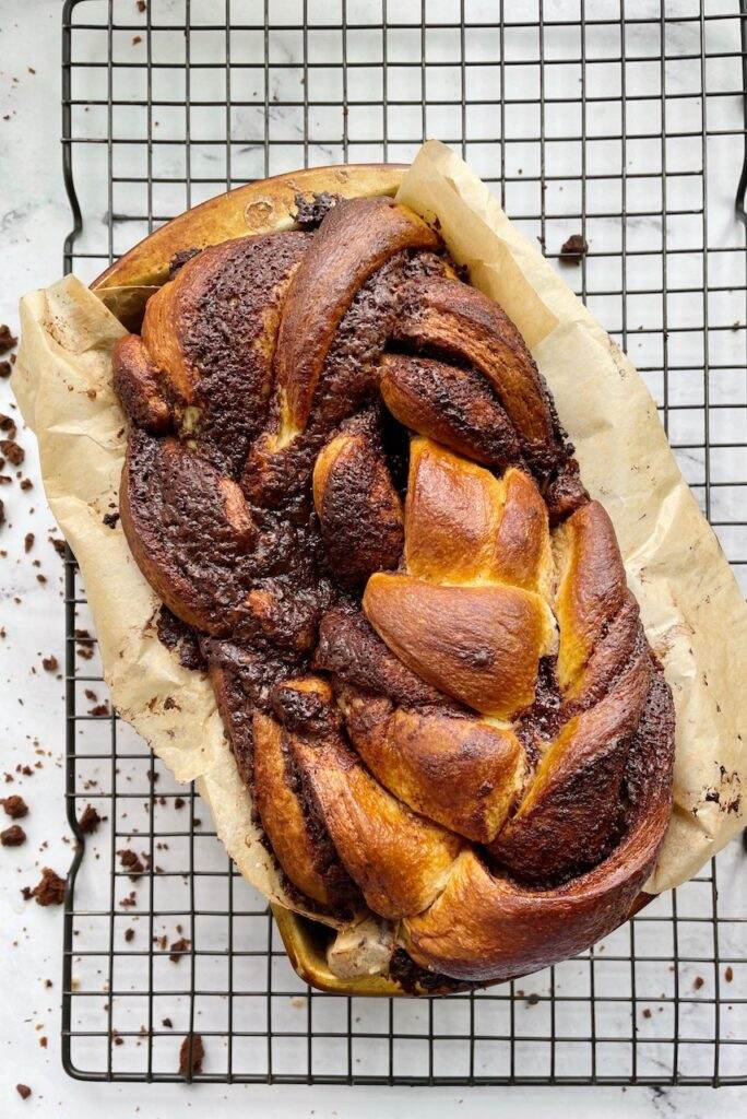 A loaf of chocolate babka on a cooking rack.