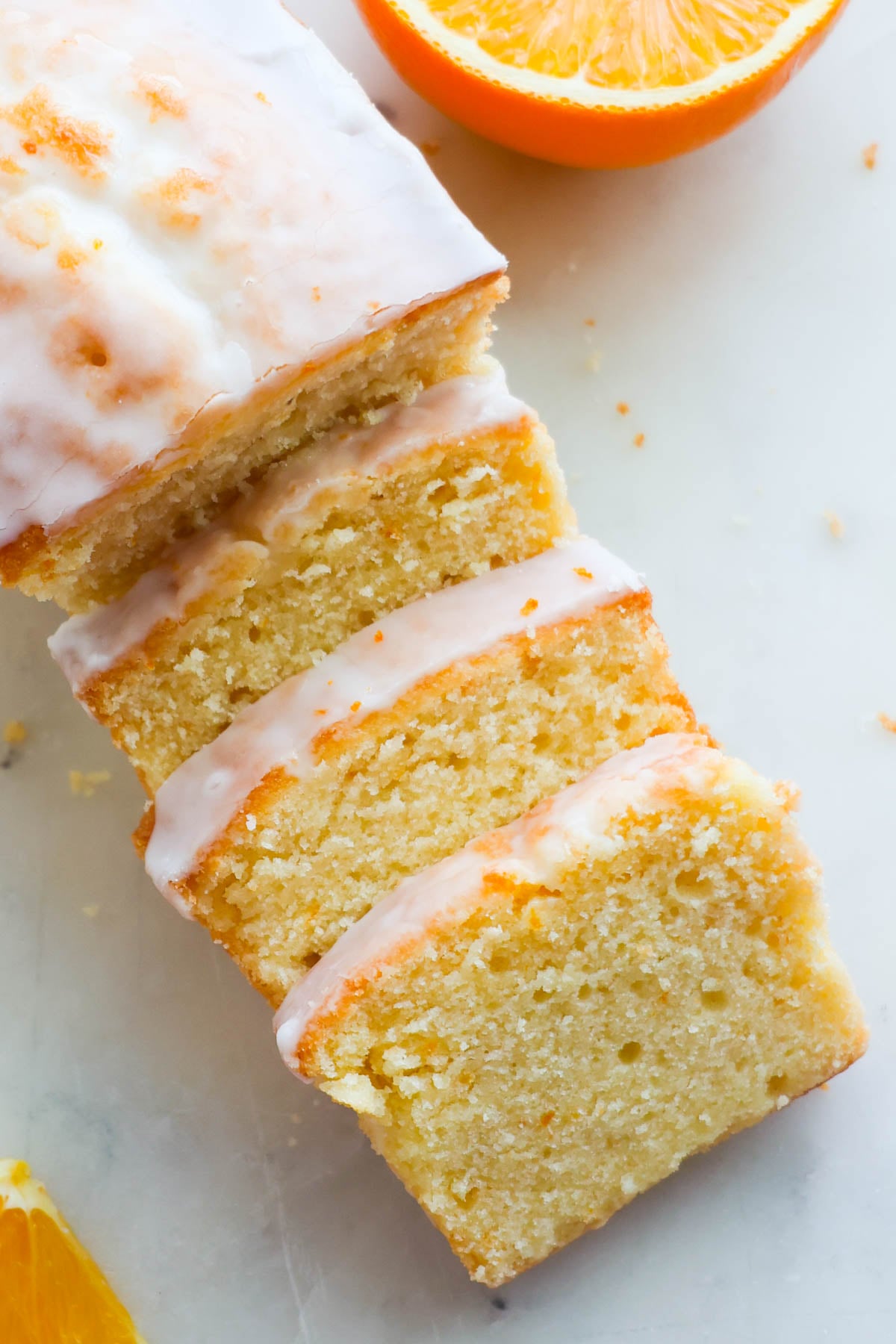 A loaf of sliced orange pound cake on a marble cutting board.