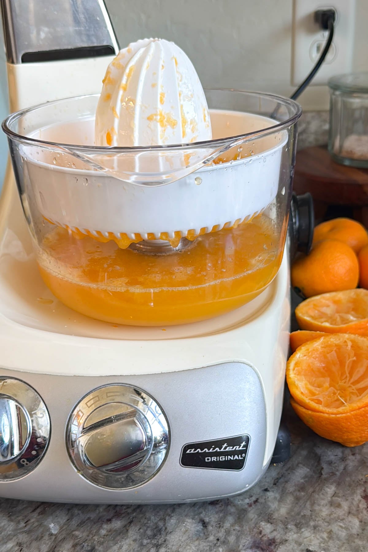 An Ankarsrum mixer with the citrus press attachment, and orange juice inside the bowl.