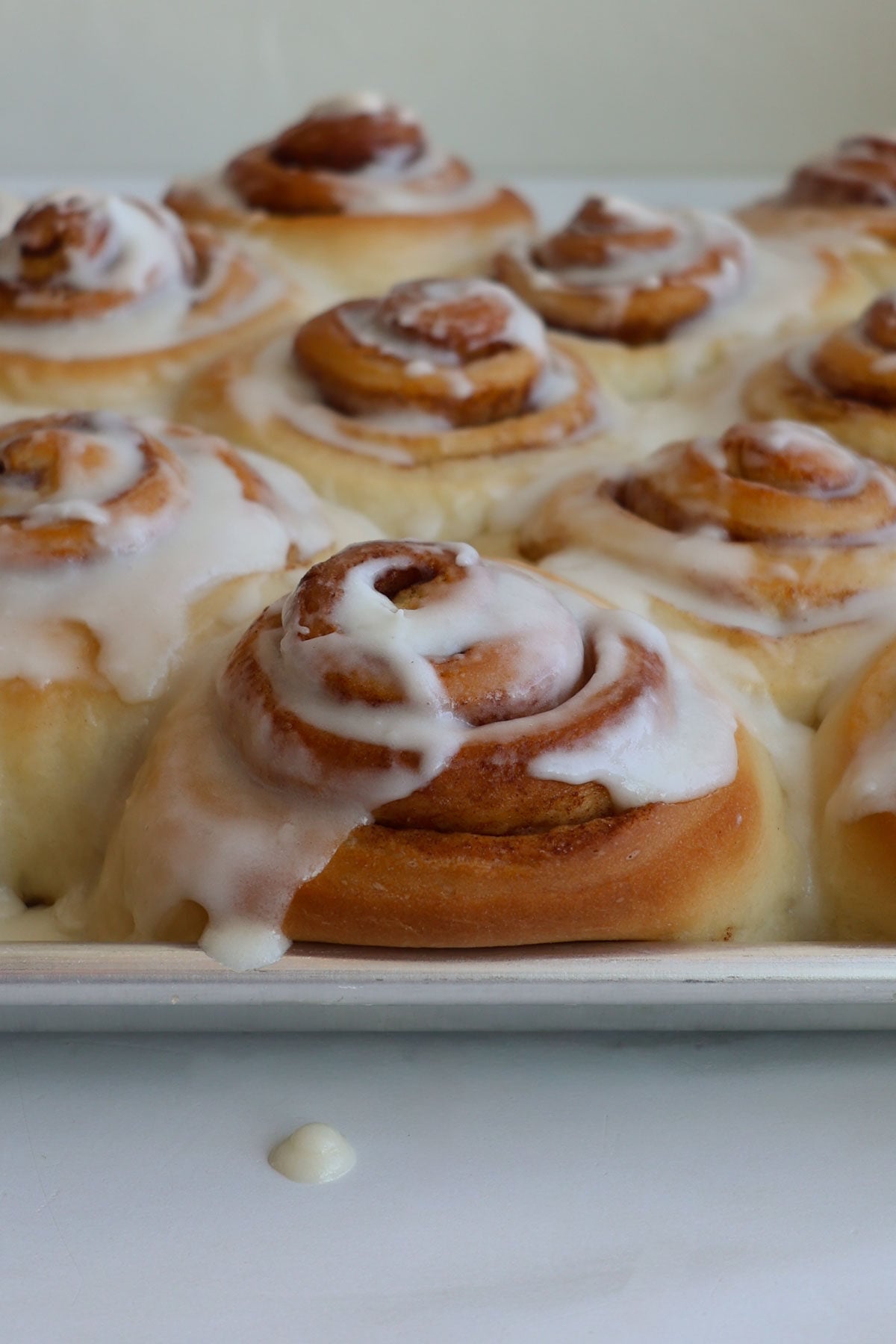 Baked homemade cinnamon rolls with cream cheese icing spread over the top.