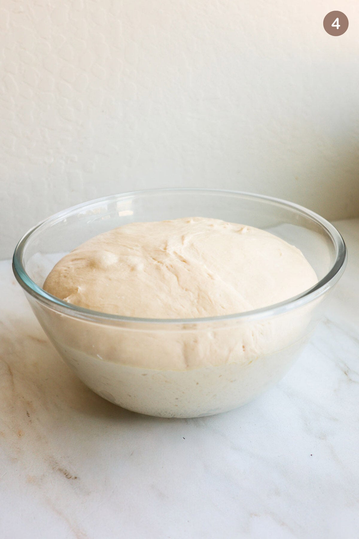 A glass bowl with risen cinnamon roll dough in it.