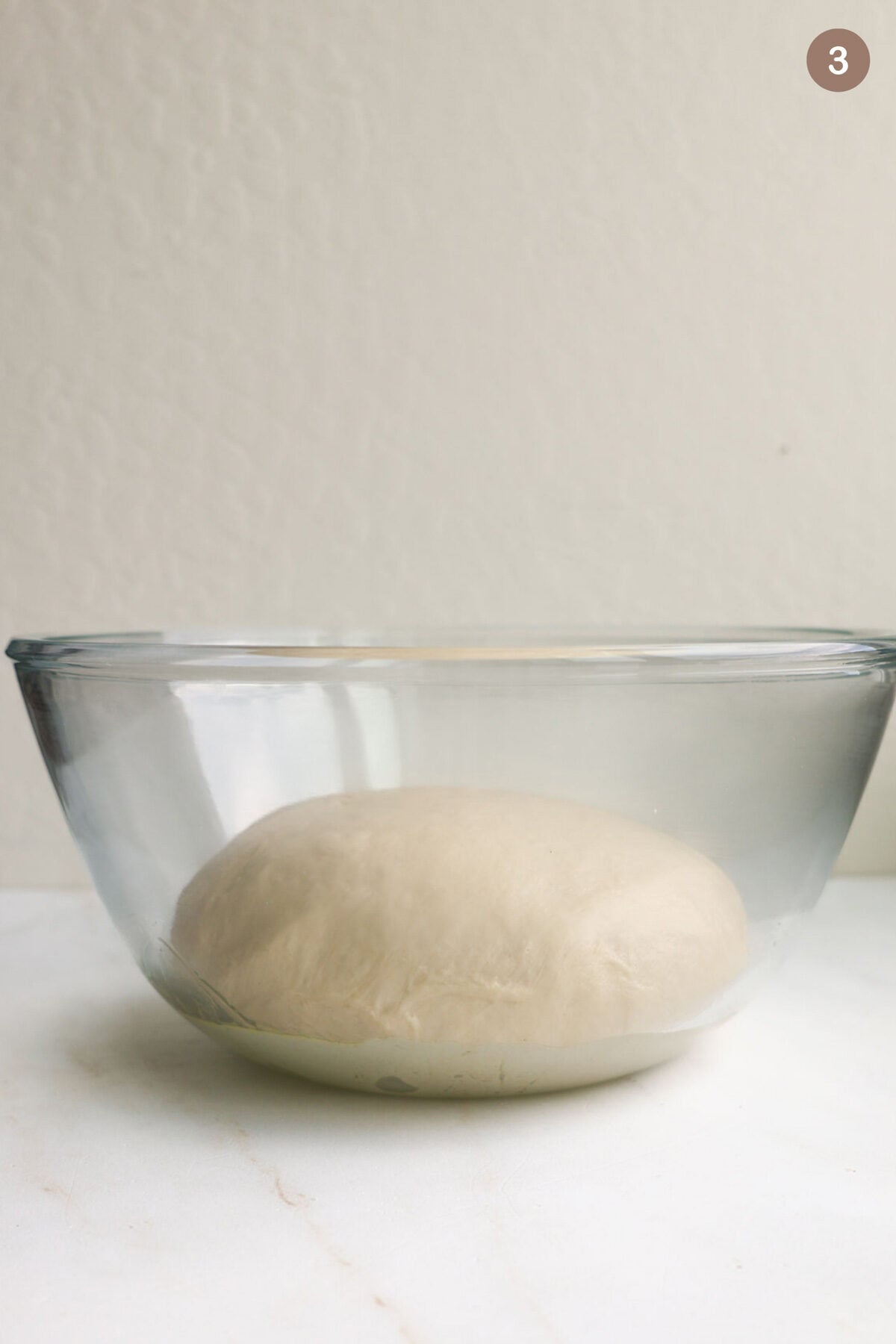 A glass bowl with cinnamon roll dough in it.