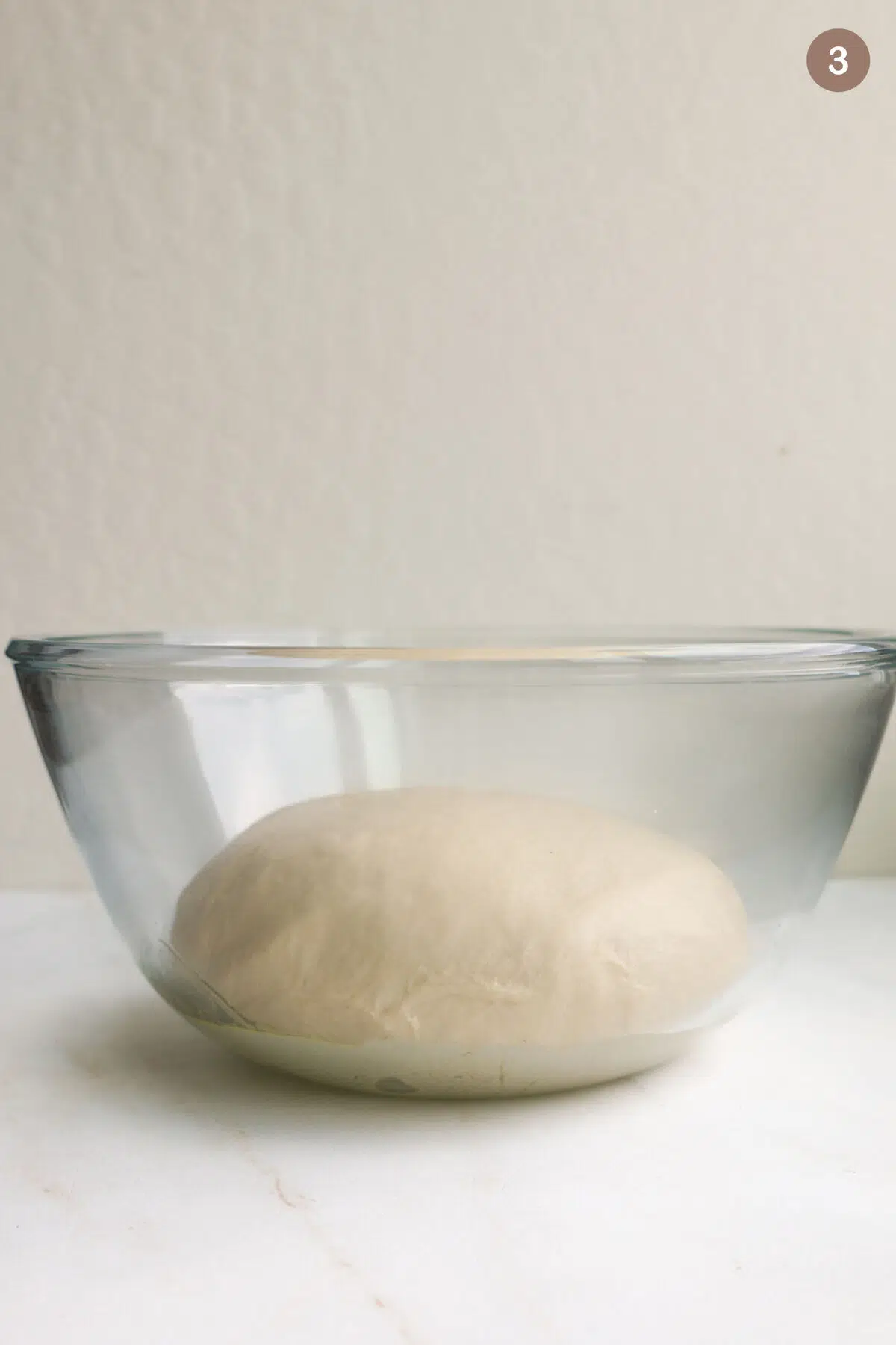 A glass bowl with cinnamon roll dough in it.