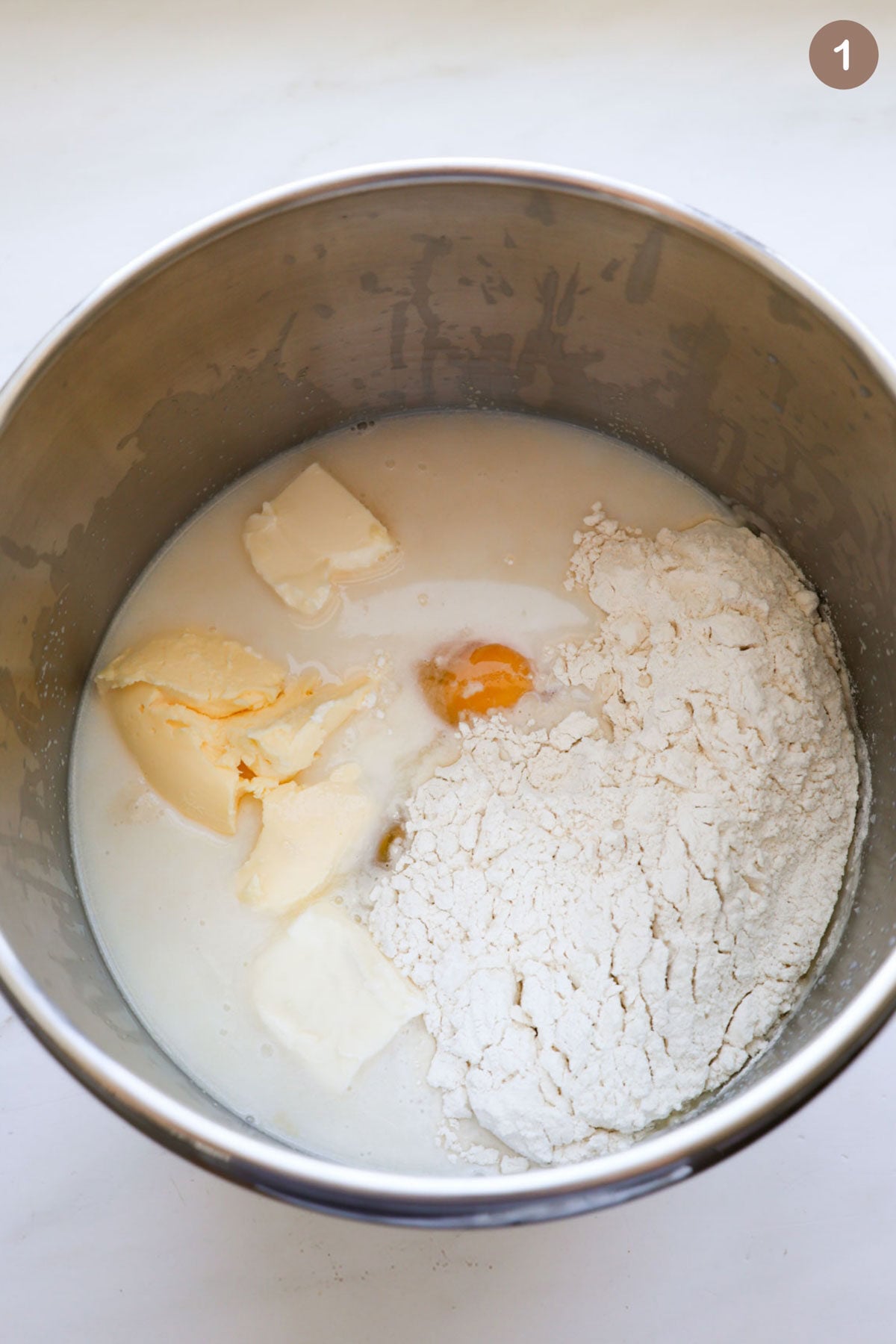 A mixing bowl with the unmixed ingredients in it for cinnamon rolls.