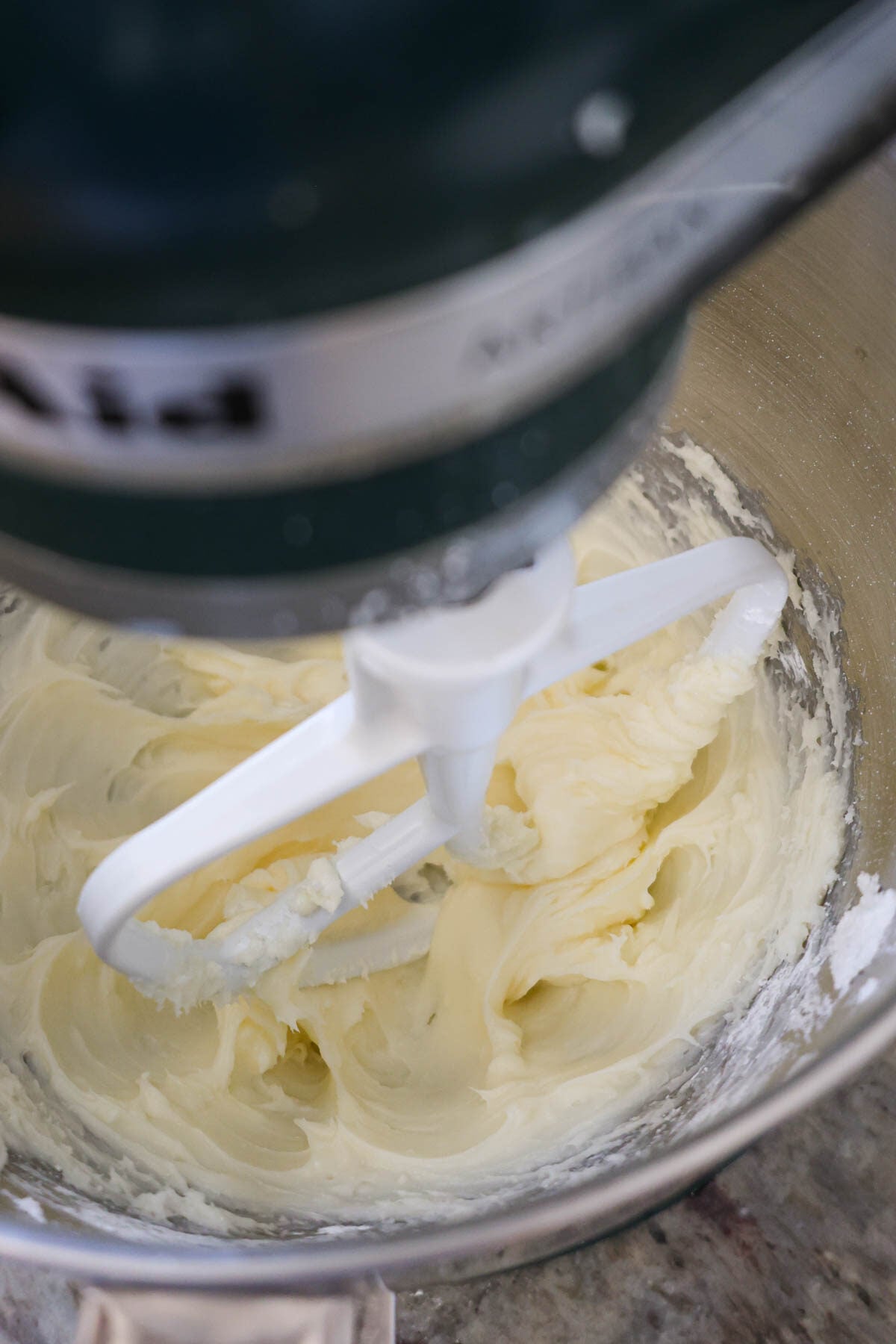 A mixer mixing cream cheese frosting with a paddle attachment.