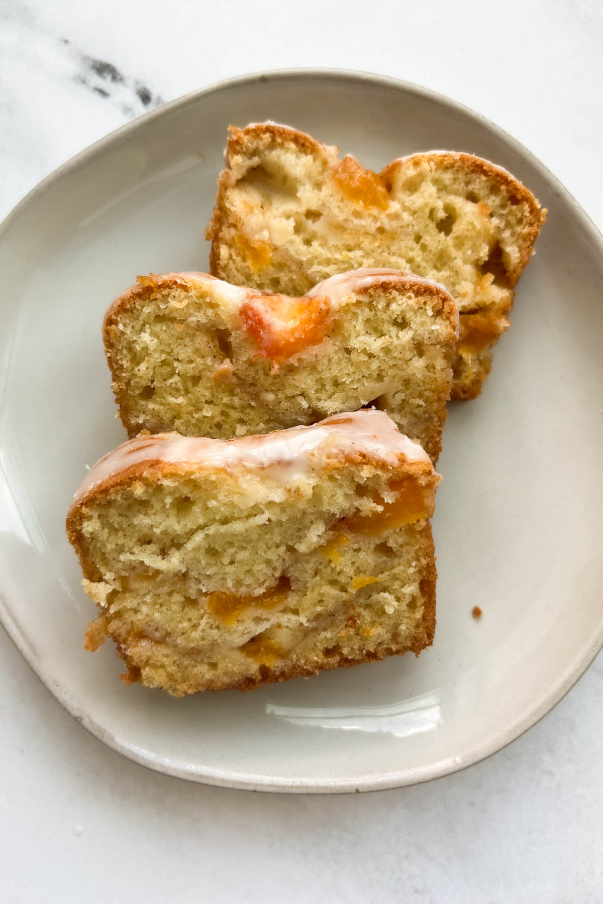 Three slices of peach cobbler bread on a white plate.