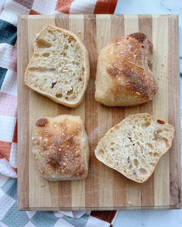 4 ciabatta rolls on a wood cutting board.