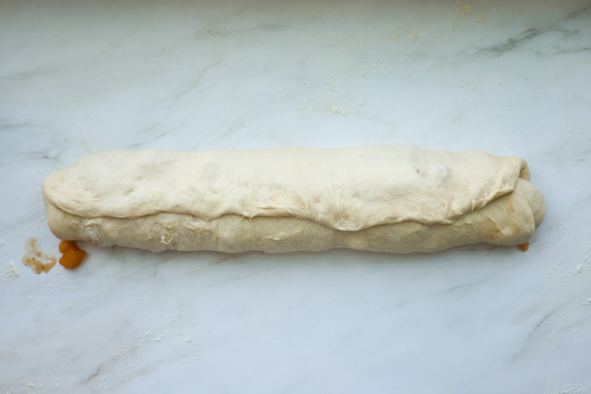 Rolled up peach cinnamon rolls, with the seam pinched shut.