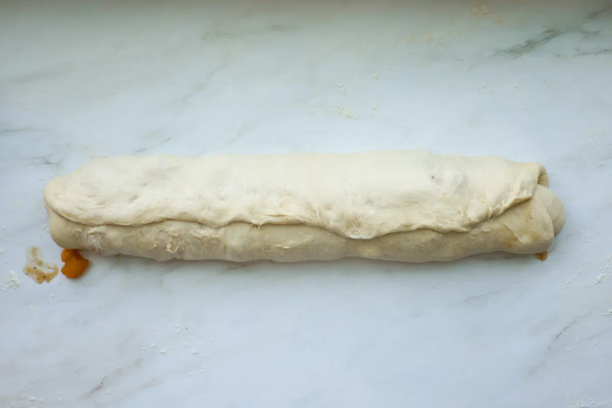 Rolled up peach cinnamon rolls, with the seam pinched shut.
