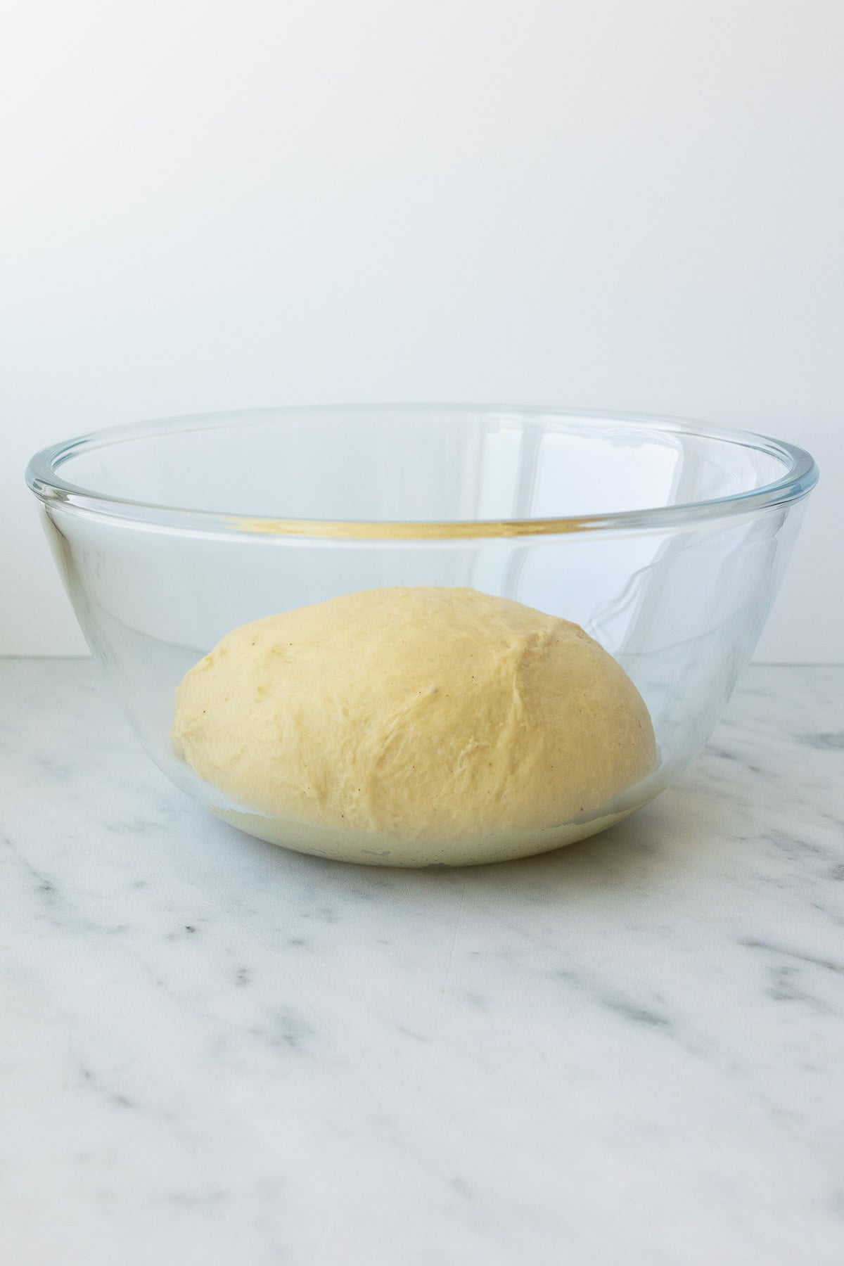 The unrisen roll dough in a glass bowl.