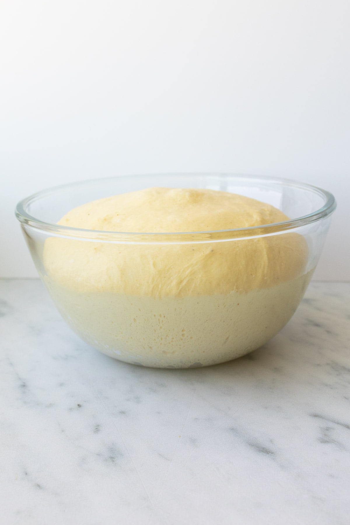 A glass bowl, with risen roll dough.