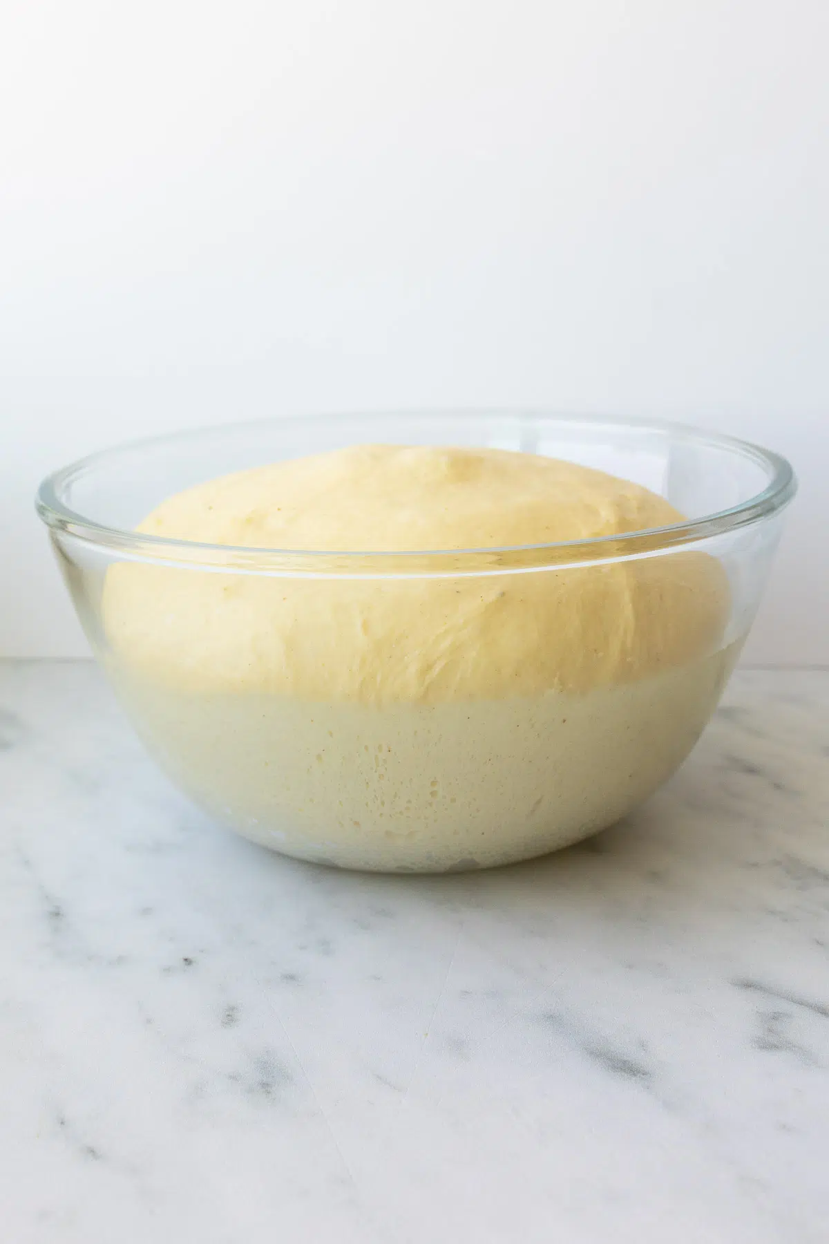 A glass bowl, with risen roll dough.