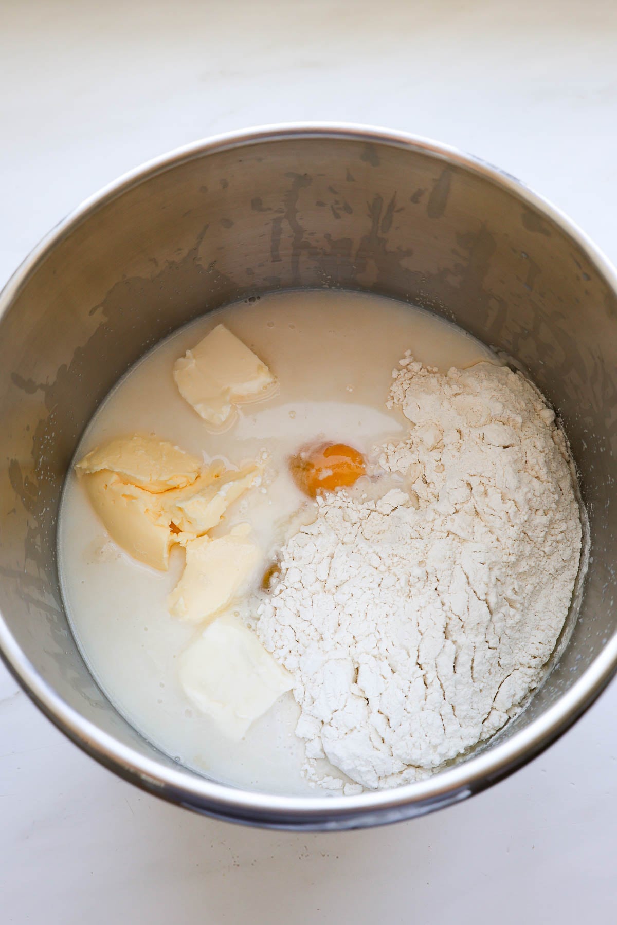 The ingredients for peach cinnamon rolls, unmixed, in a stainless steel mixer bowl.