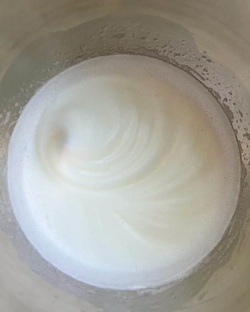 A stainless steel bowl with medium soft mixture of egg whites.