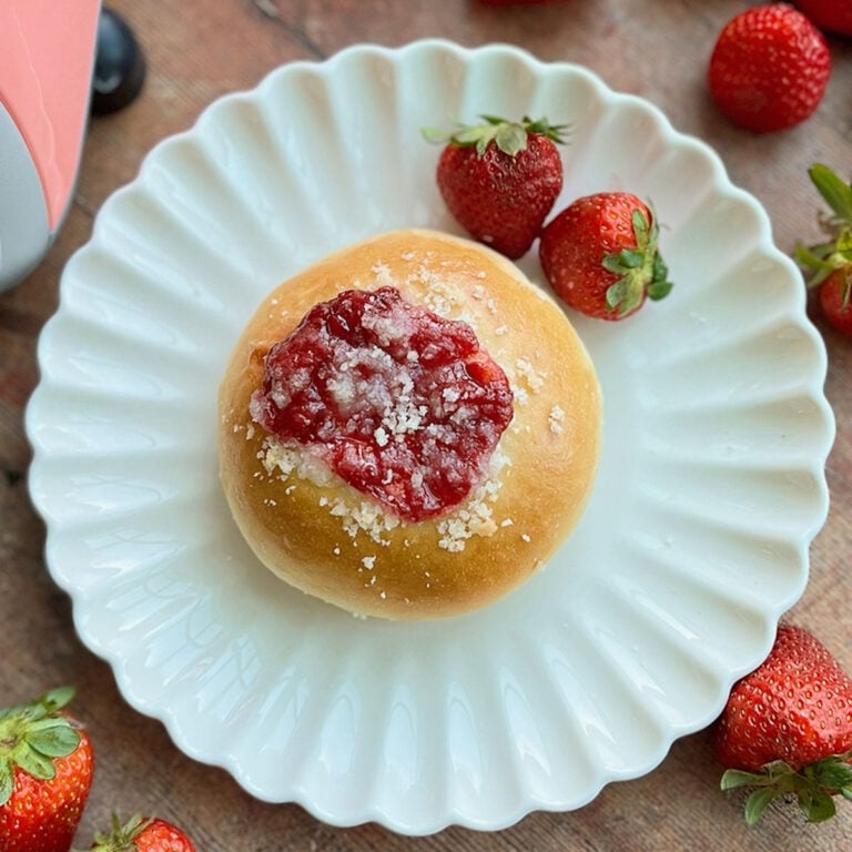 A strawberry cream cheese pastry on a plate with strawberries.