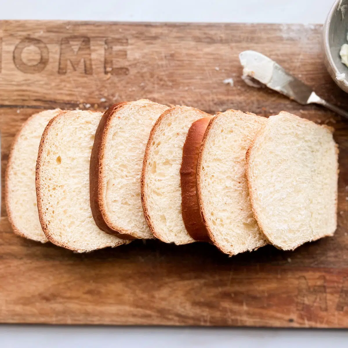 Slices of white sandwich bread on a wood cutting board.