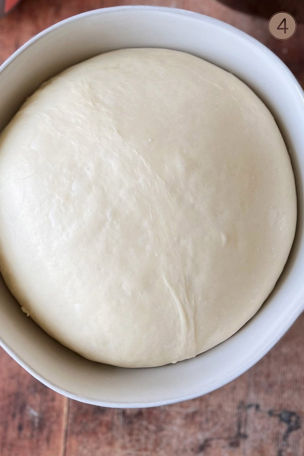 A white bowl with dough risen inside.