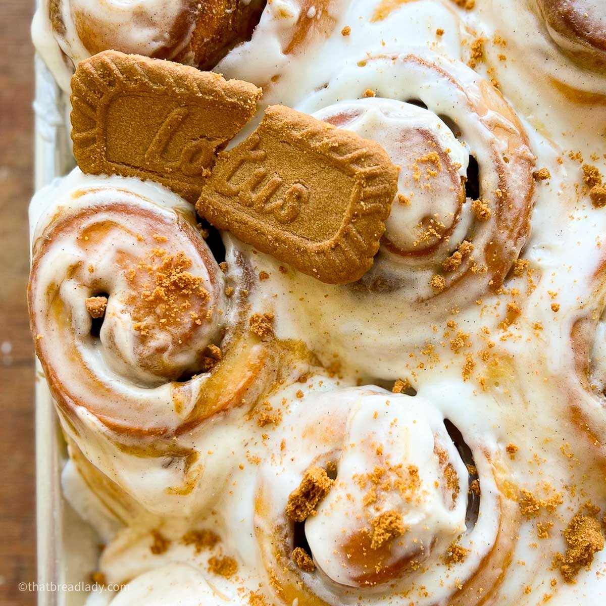 Biscoff cinnamon rolls in a baking sheet with Lotus cookie crumles on top.