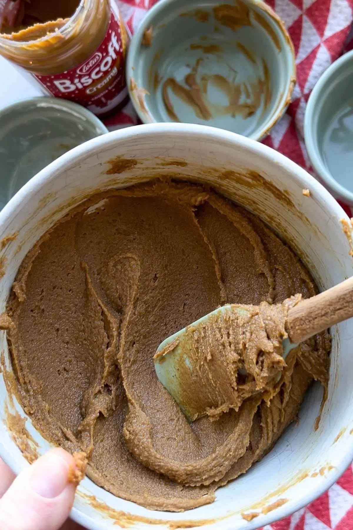 A bowl of biscoff cinnamon roll filling, with a silicone spatula stirring it.
