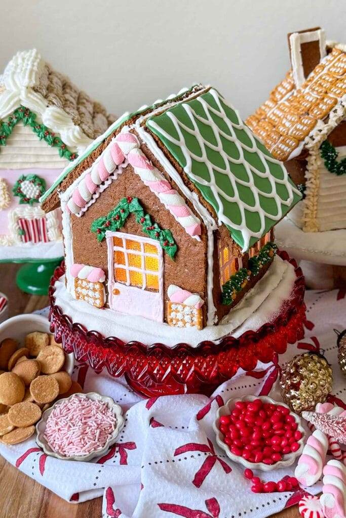 A decorated gingerbread house with different kinds of candy in bowls.