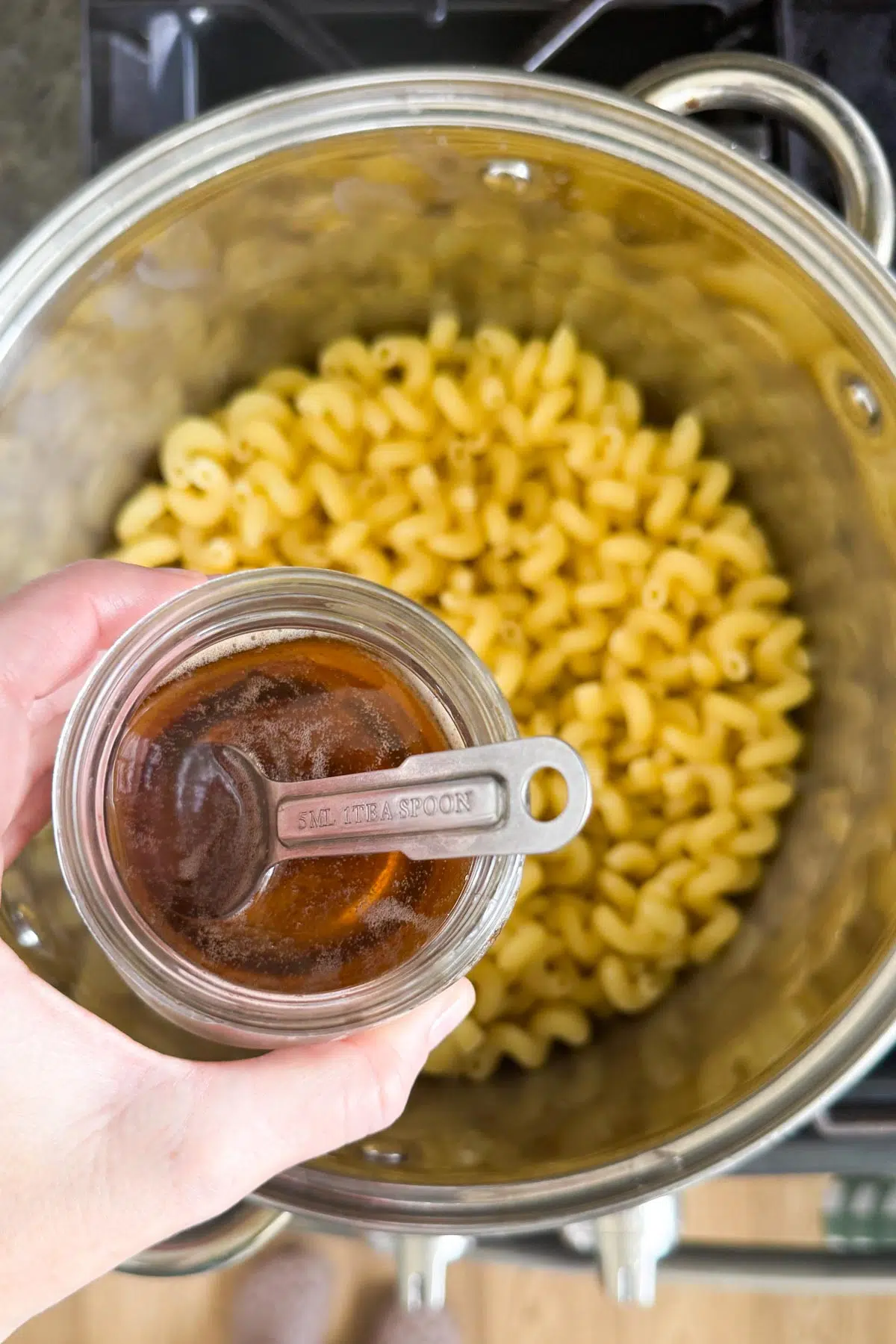 A jar of bacon drippings and a pot of cooked macaroni.