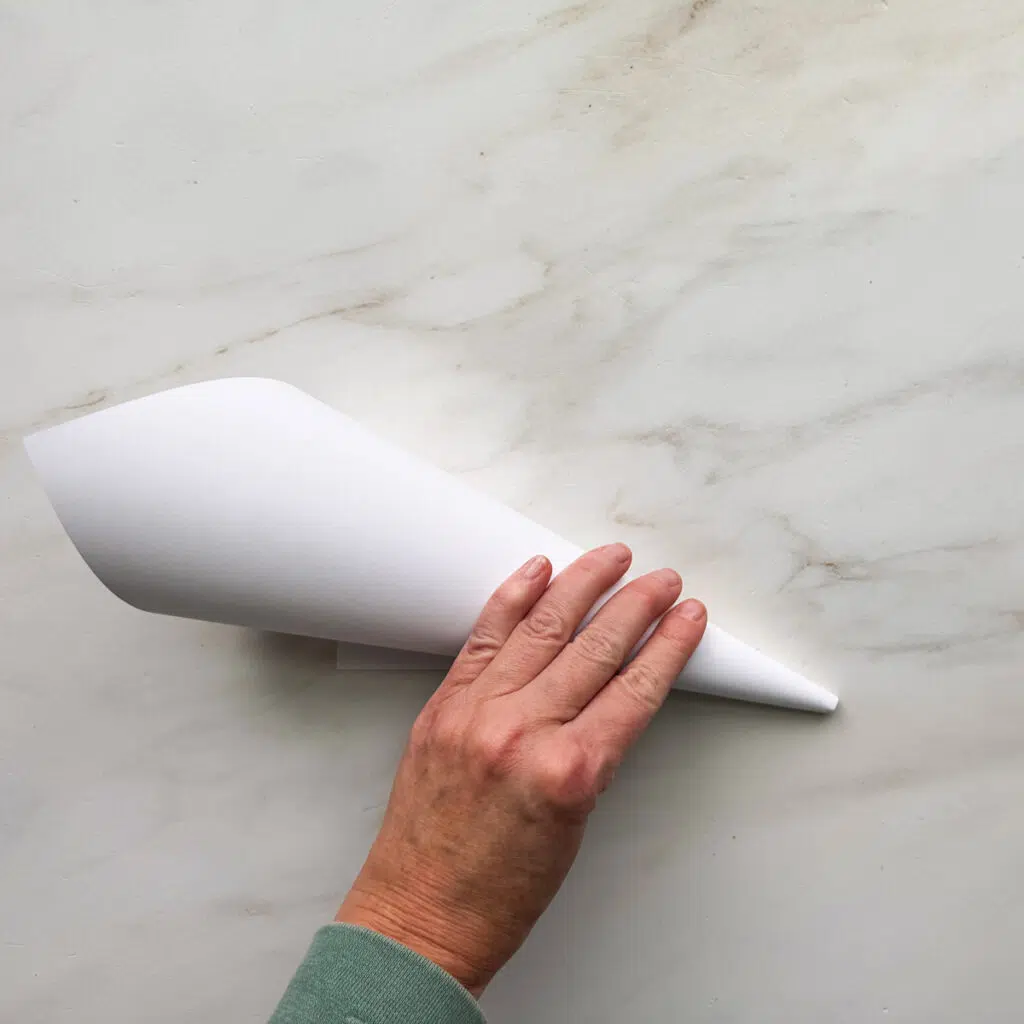 A white 8.5 by 11-inch piece of paper rolled up to a cone shape.