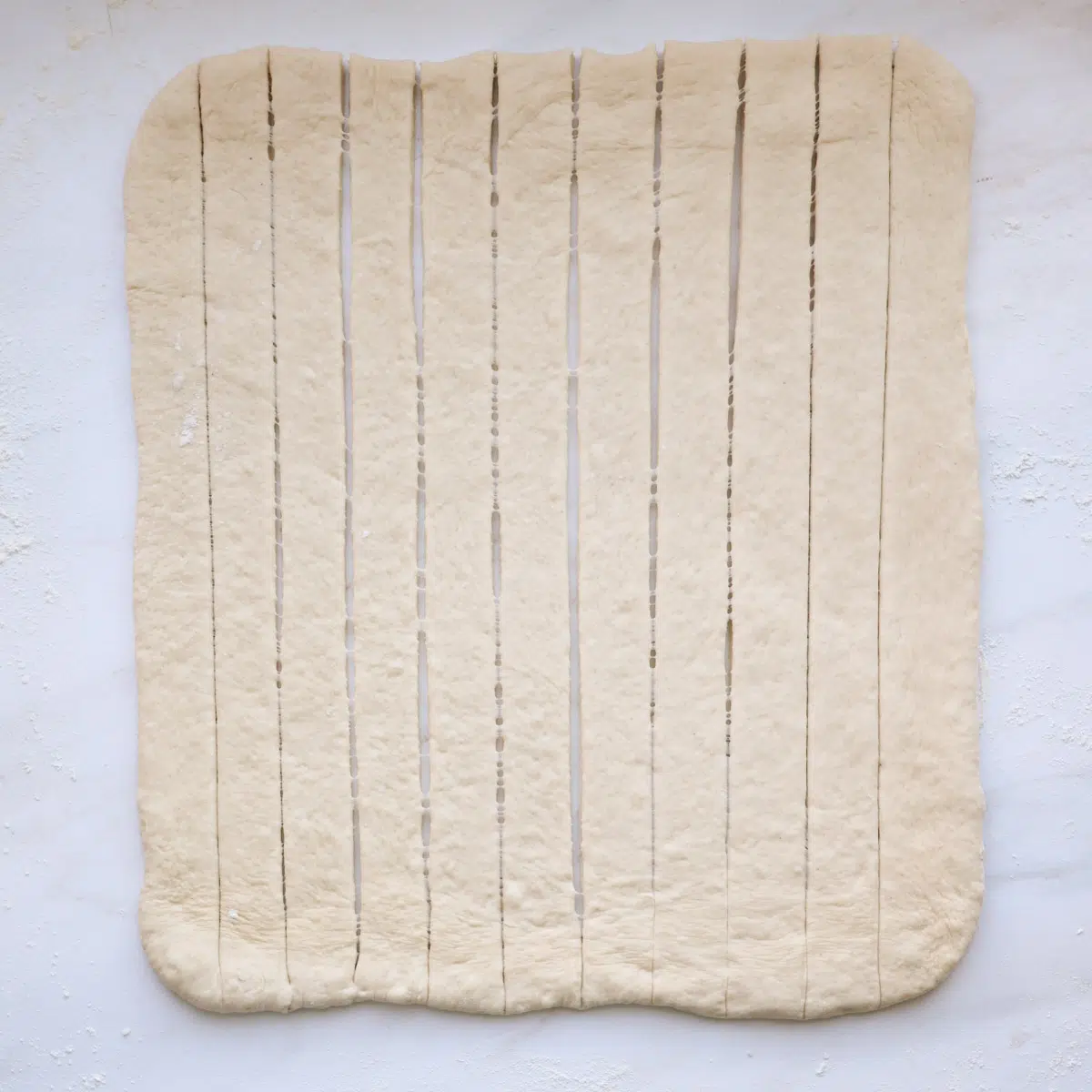 A 12 by 18-inch rectangle of bread dough, cut into 12, 1-inch strips.