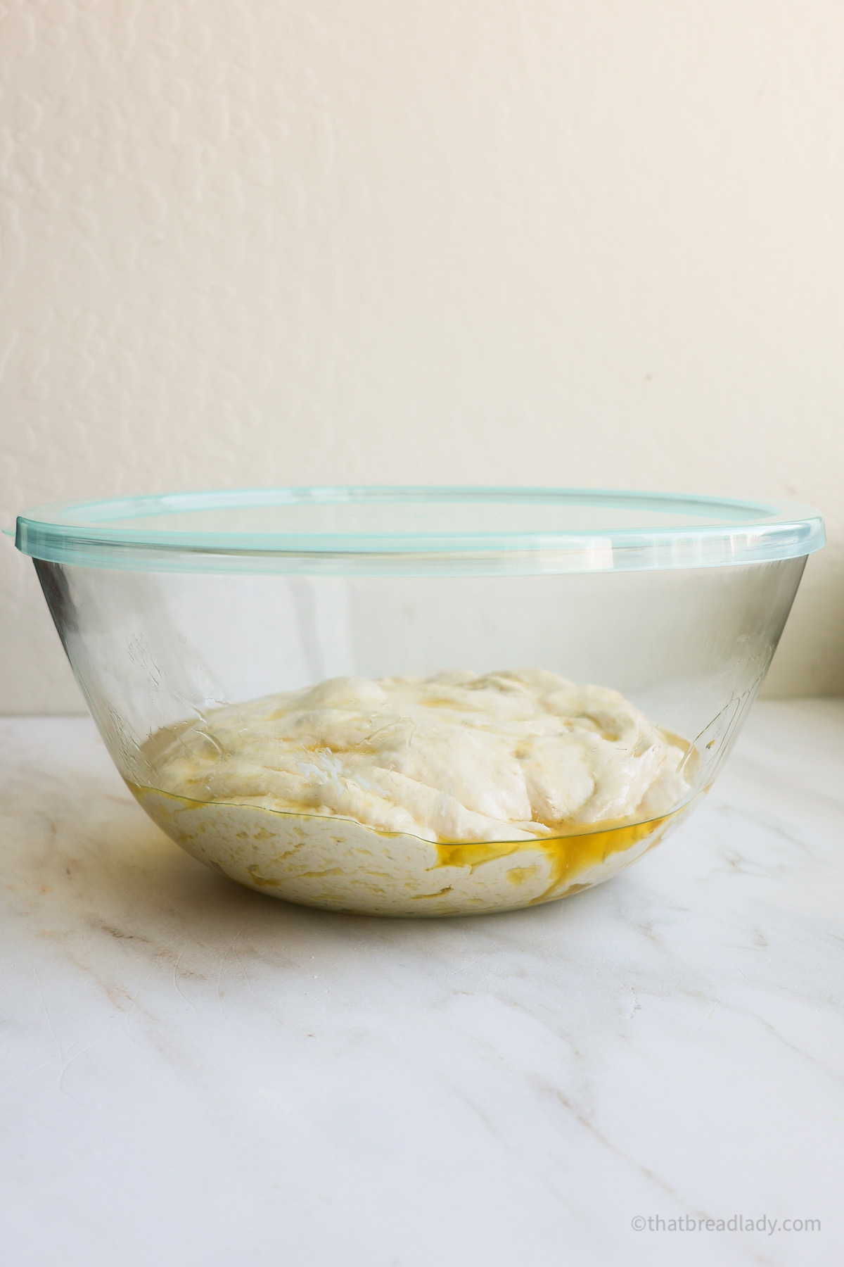 A glass bowl with focaccia dough in it.