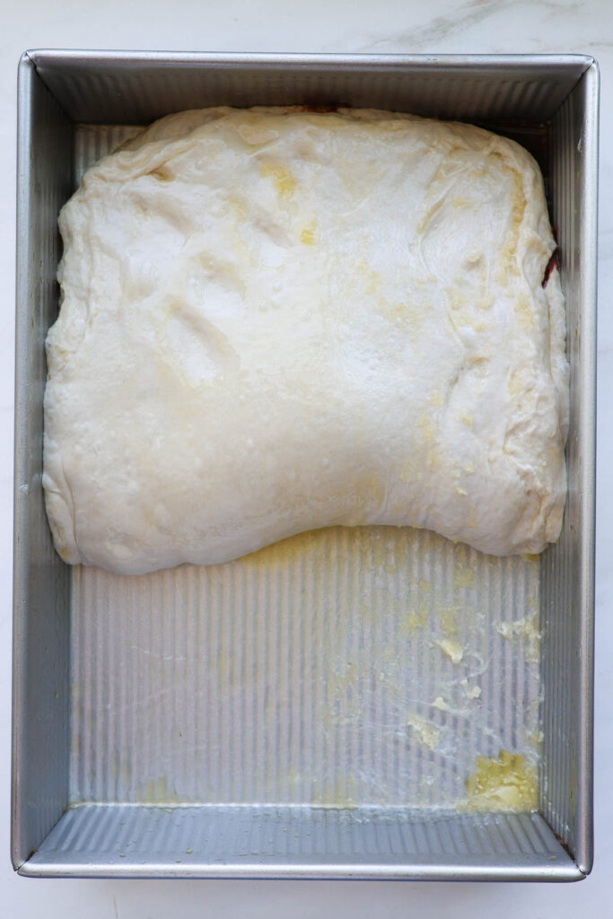 Cinnamon roll focaccia dough folded over in half with the cinnamon sugar filling inside.
