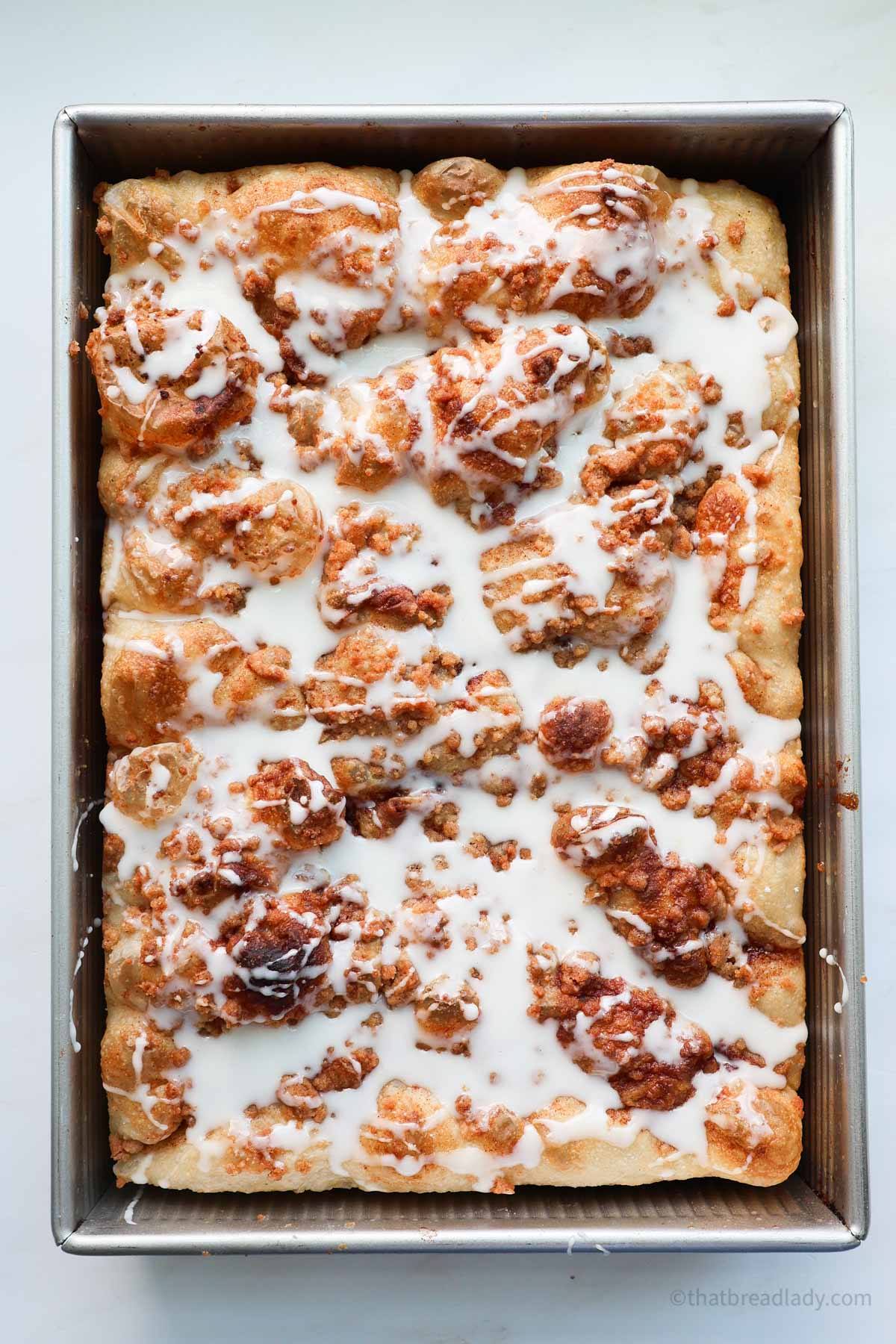 Cinnamon Roll Focaccia in a pan with vanilla icing on top.