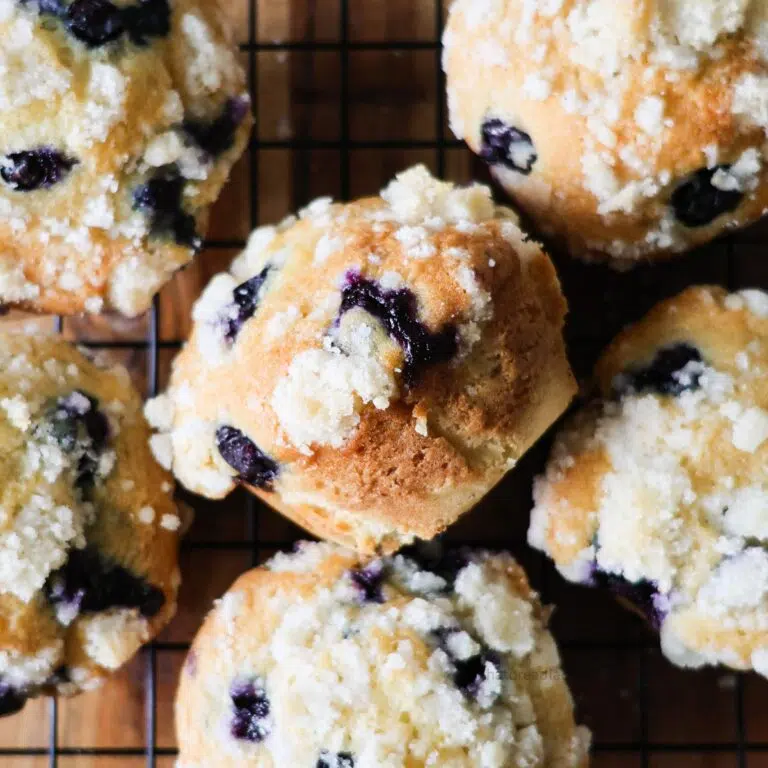 A bunch of sourdough discard blueberry muffins on a wire cooling rack.