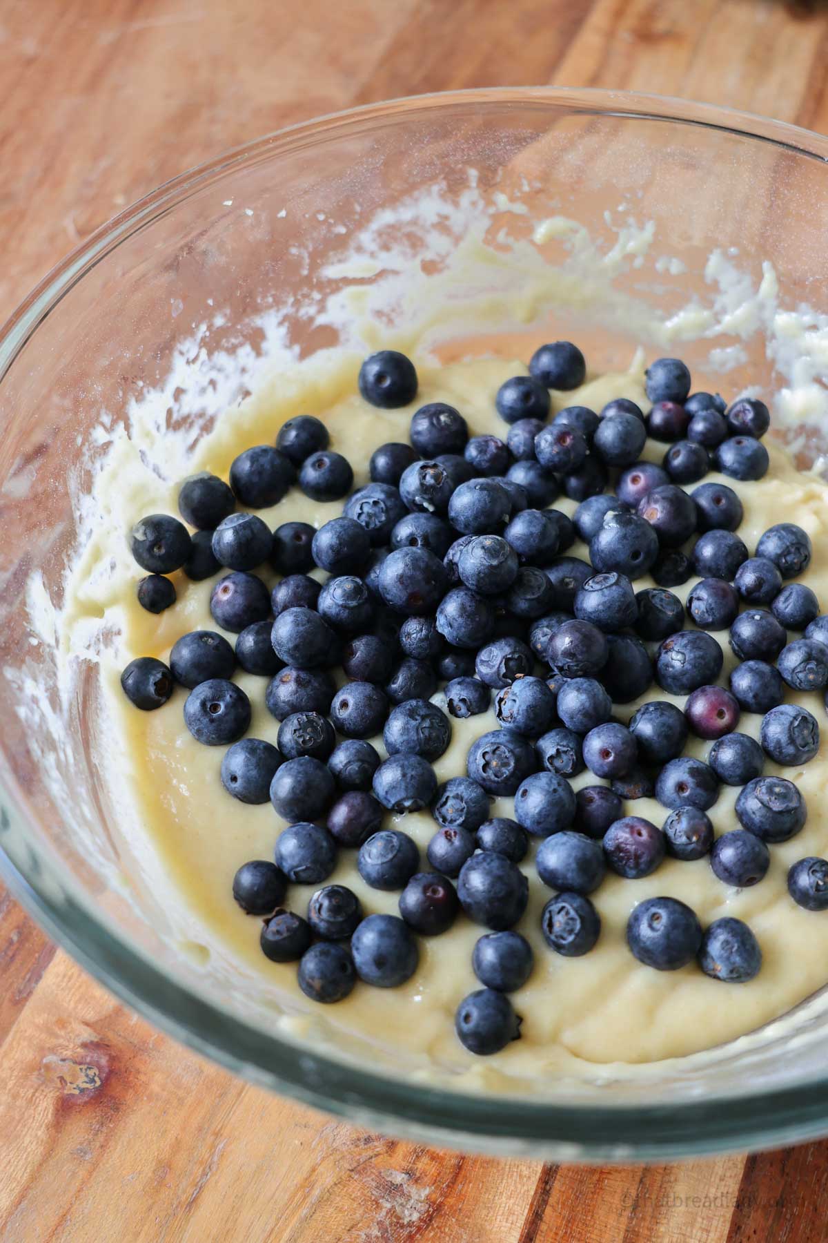 A bowl of muffin batter with blueberries in it.