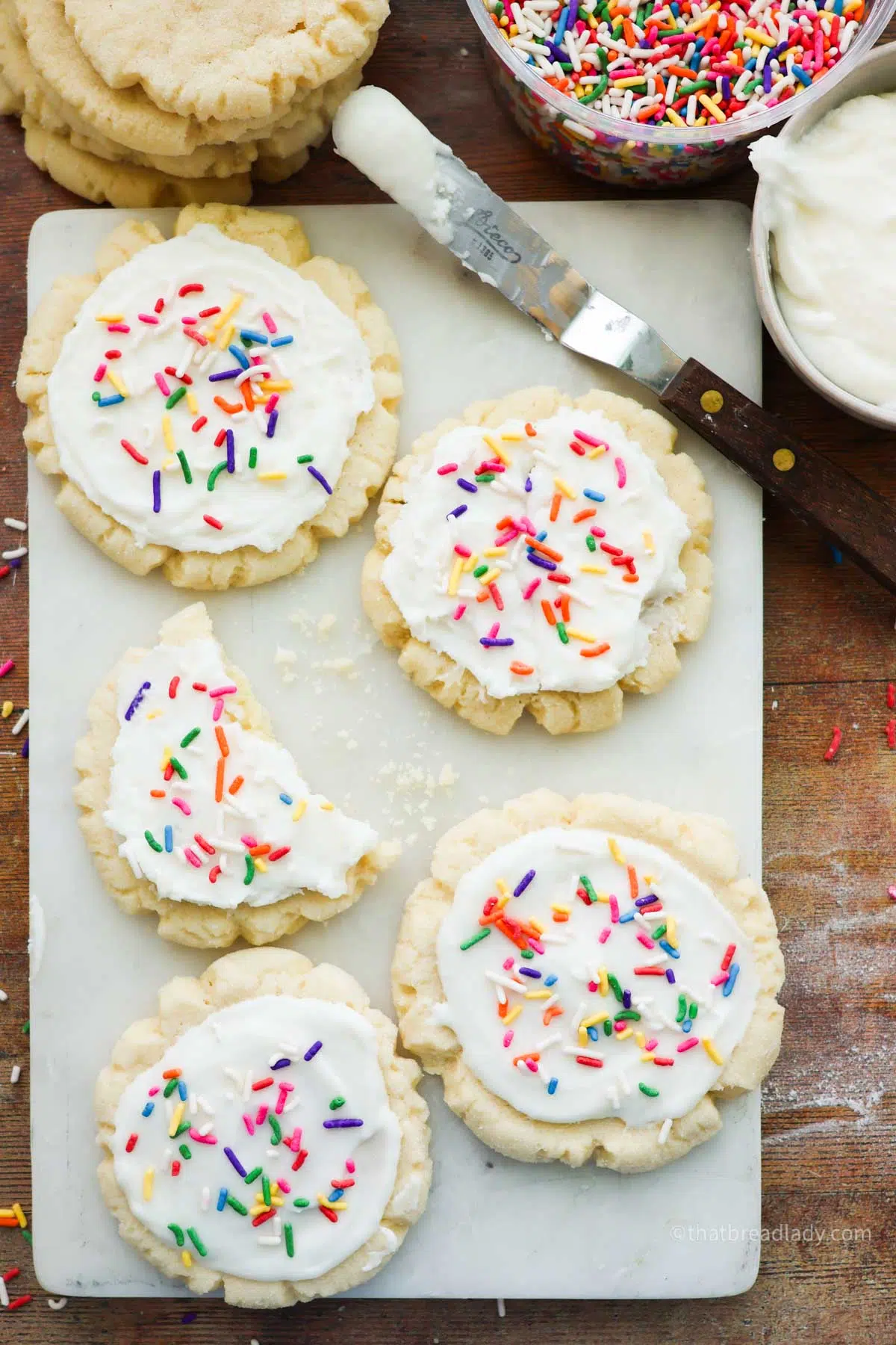 Sourdough sugar cookies with colorful sprinkles on a white marble cutting board.