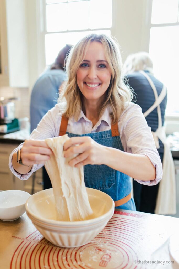 Heather Thomas, That Bread Lady, in a kitchen, mixing sourdough bread.