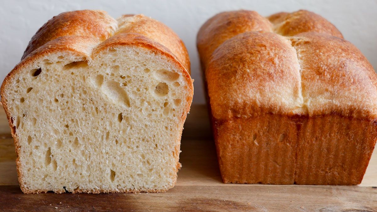 Two loaves of homemade bread, one sliced and one unsliced.