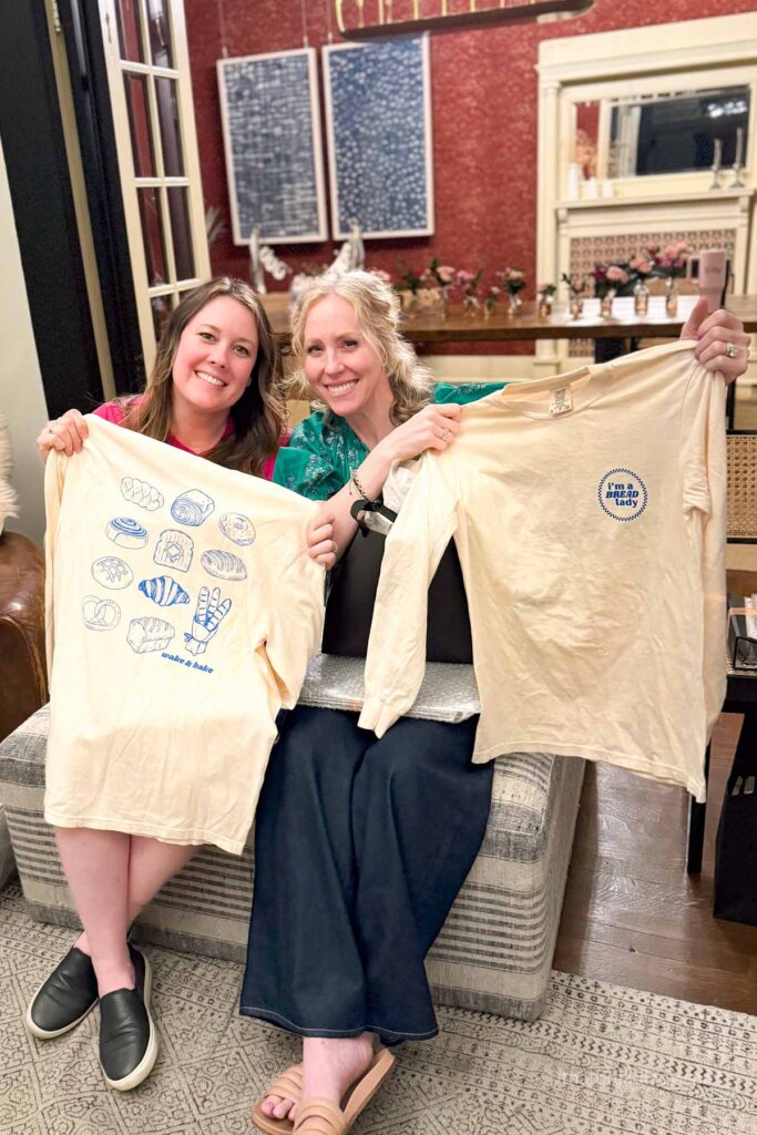 Two ladies at Heather's baking retreat, holding up bread lady tshirts.