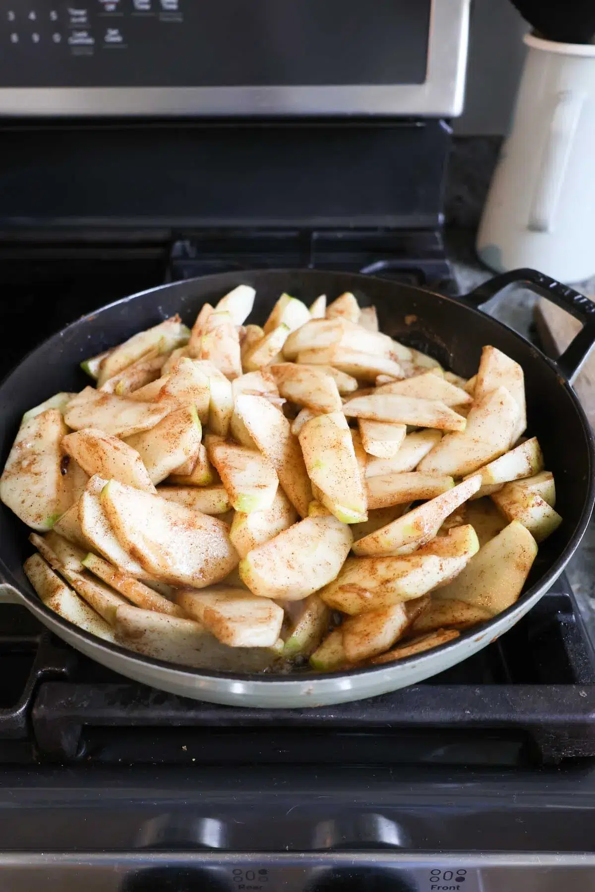 Sliced cinnamon apples in a saucepan on the stove.