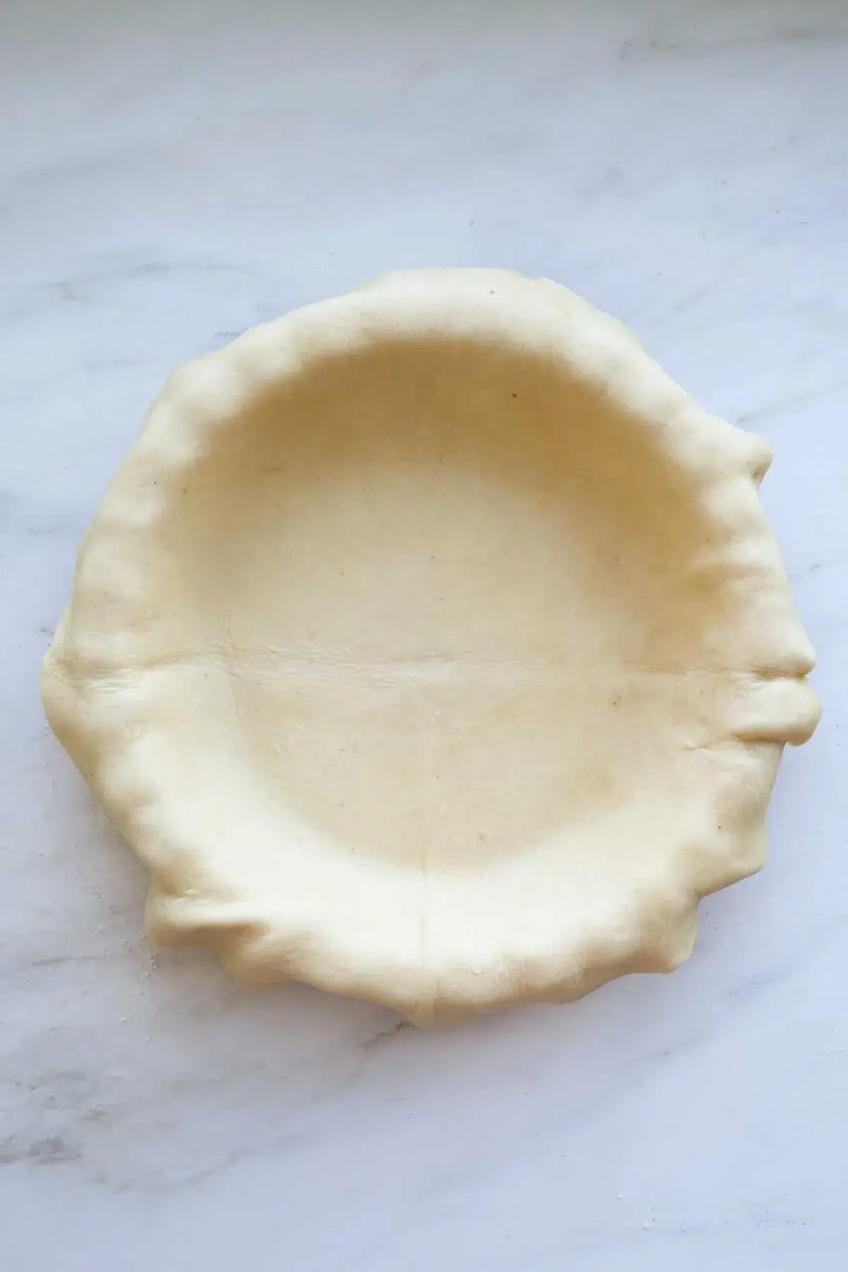 An unbaked, unshaped pie crust, resting in a pie pan.